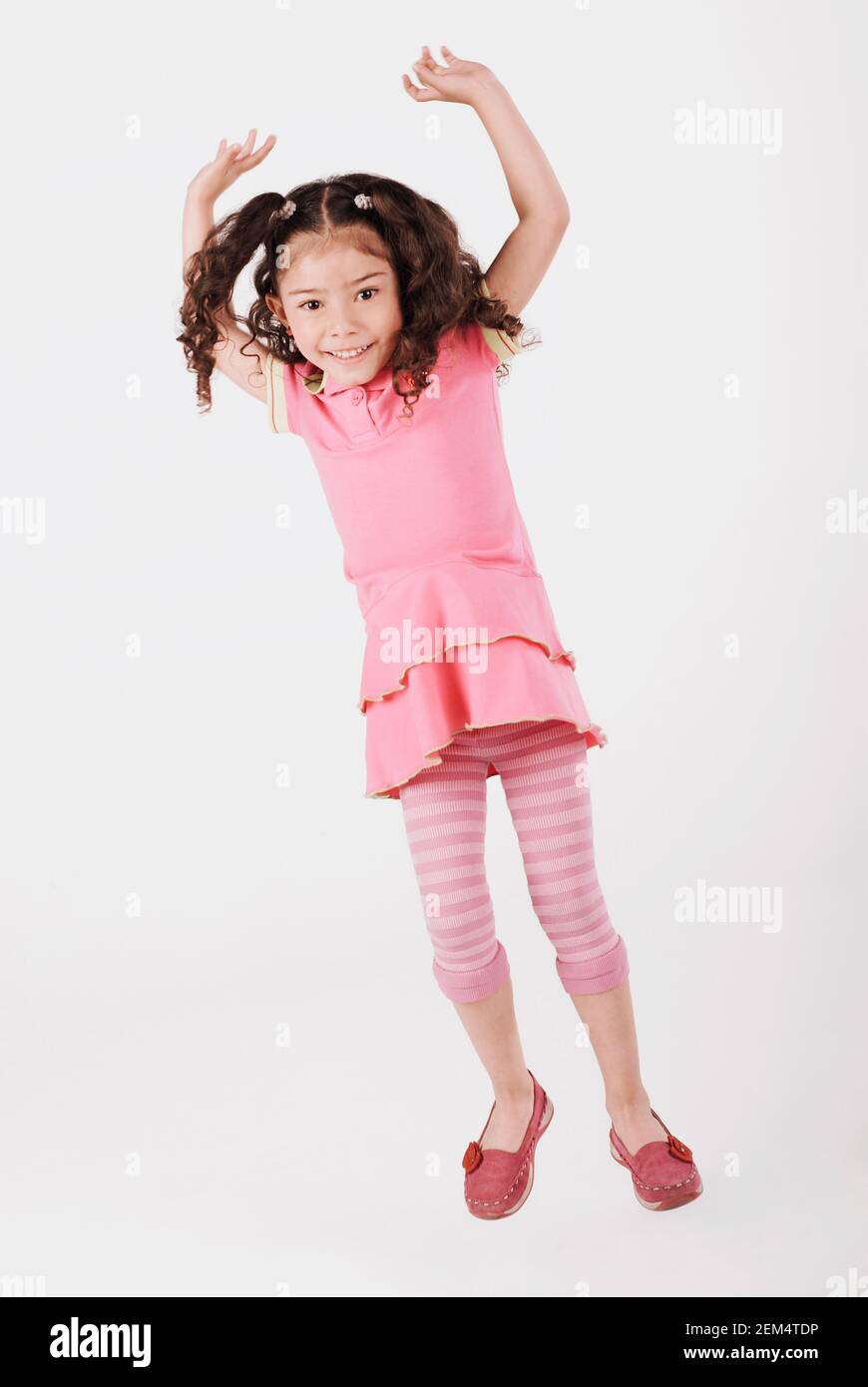 Portrait eines Mädchens, das mit erhobenen Armen springt und Lächelnd Stockfoto