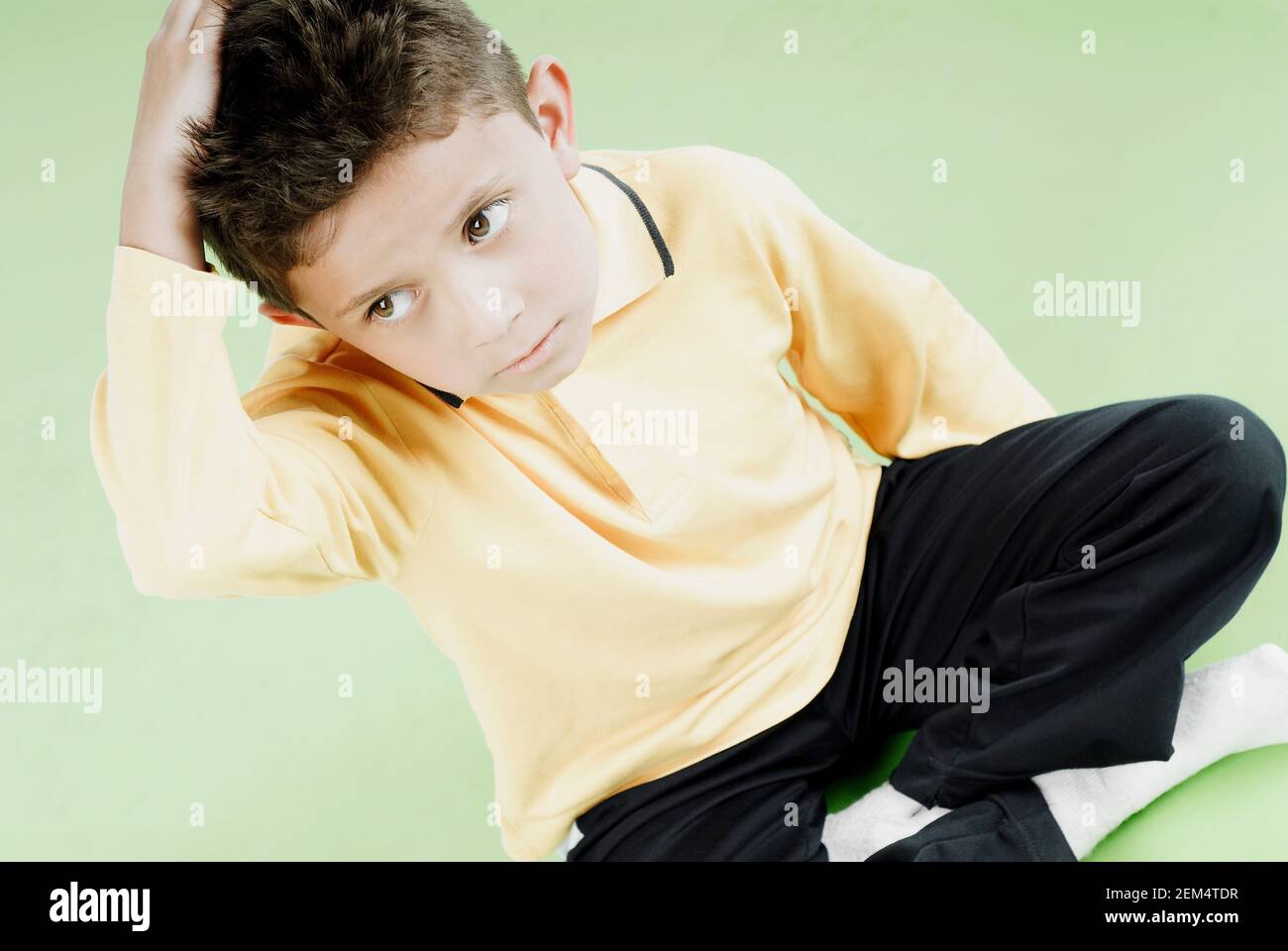 Hochwinkelansicht eines Jungen, der mit seinen Beinen sitzt Gekreuzt Stockfoto