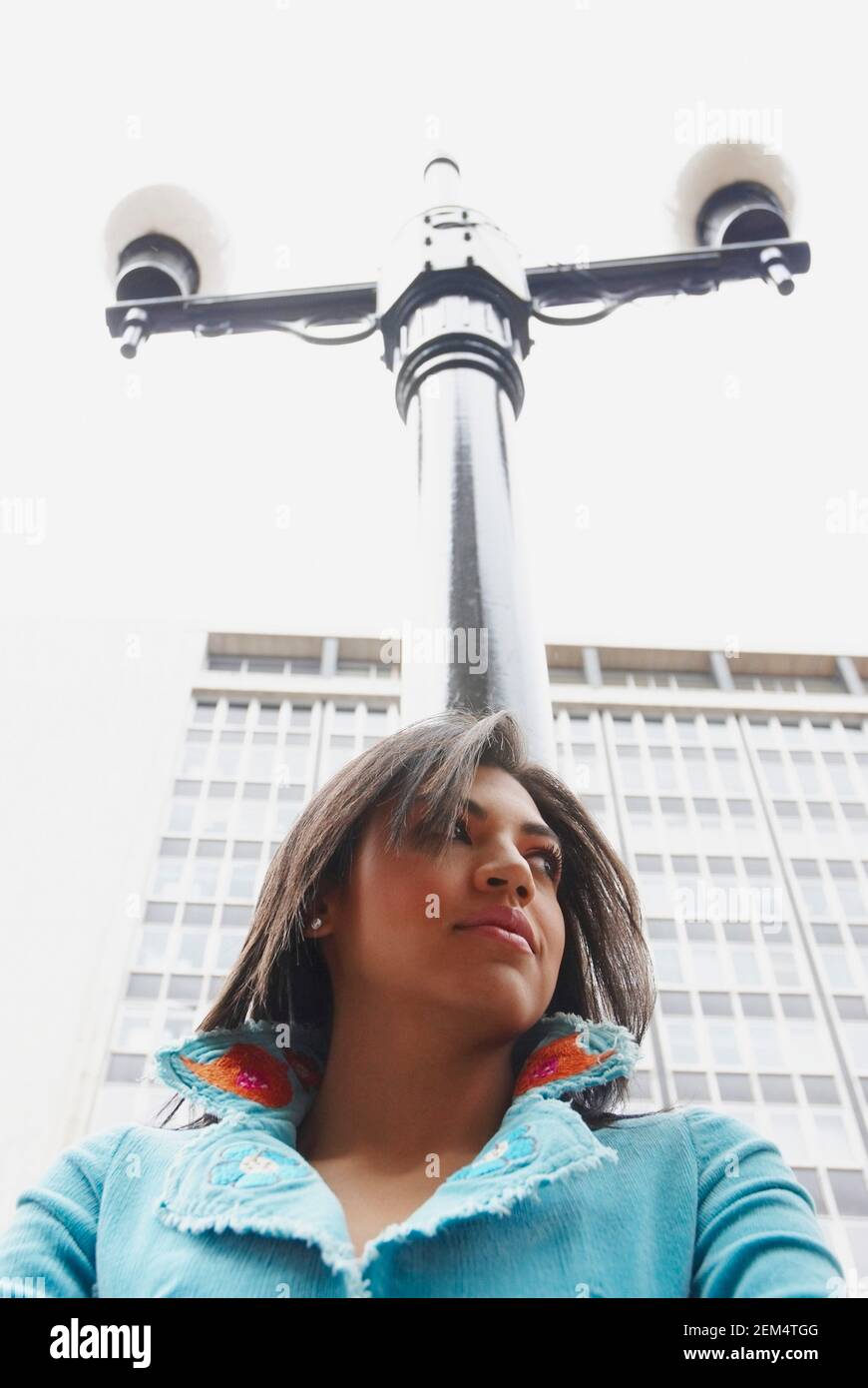 Low-Angle-Ansicht einer jungen Frau mit einem Laternenpfahl Stockfoto