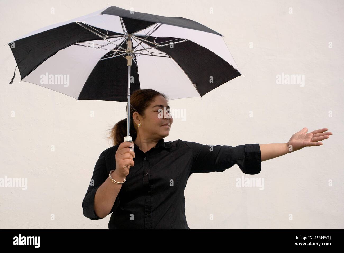 Nahaufnahme einer reifen Frau, die einen Regenschirm hält und gestikiert Stockfoto