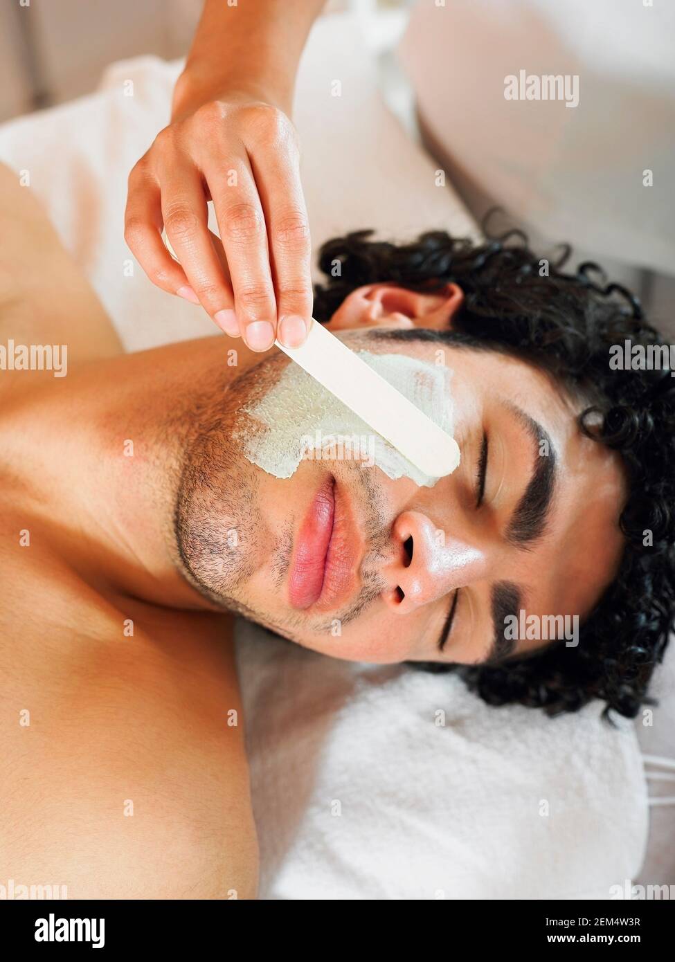 Nahaufnahme eines jungen Mannes, der eine Gesichtsmaske bekommt Stockfoto