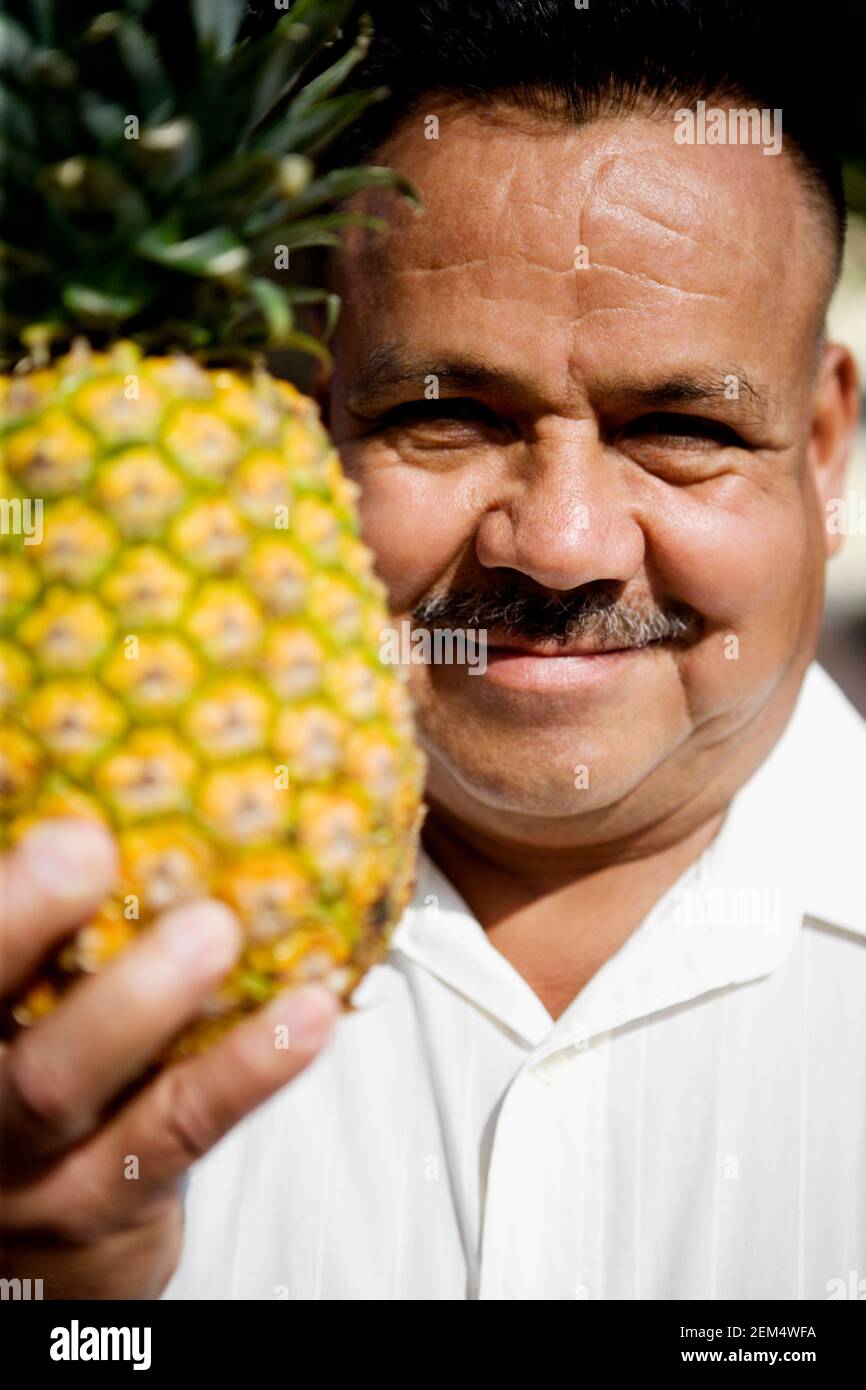 Porträt eines reifen Mannes mit Ananas und Lächeln Stockfoto