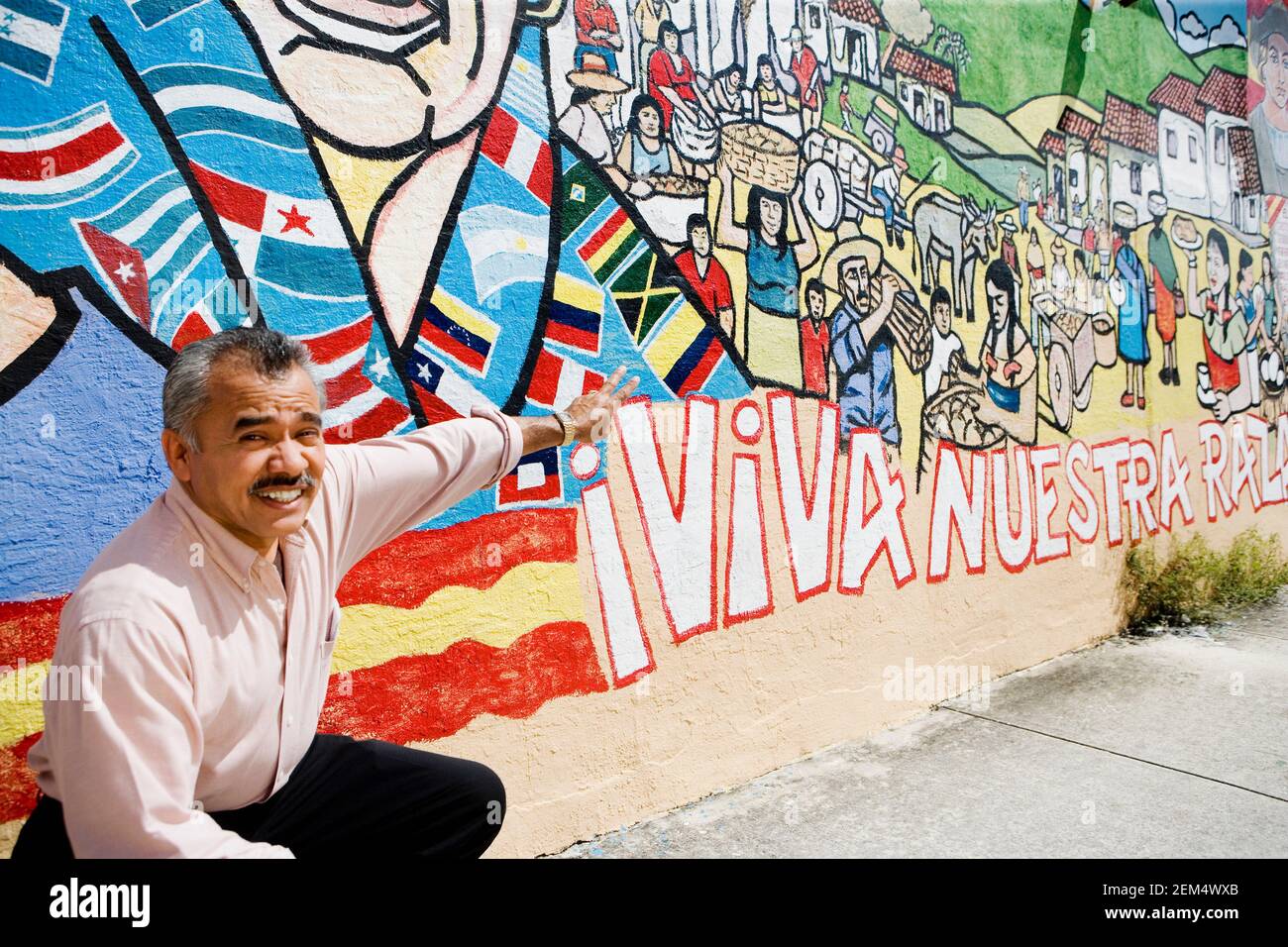 Porträt eines reifen Mannes, der vor einem hockend Graffiti Wand und ein Friedenszeichen Stockfoto