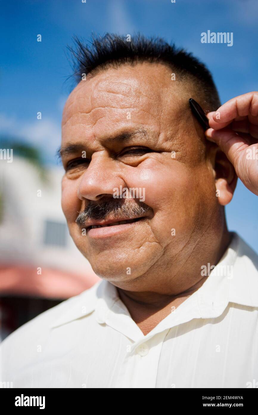 Porträt eines reifen Mannes, der einen Stift hinter sich hält Ohr und Lächeln Stockfoto