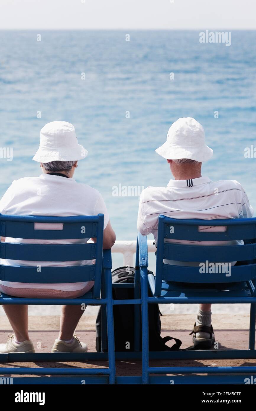 Rückansicht eines älteren Ehepaares, das auf Stühlen am Strand sitzt, Barcelona, Spanien Stockfoto