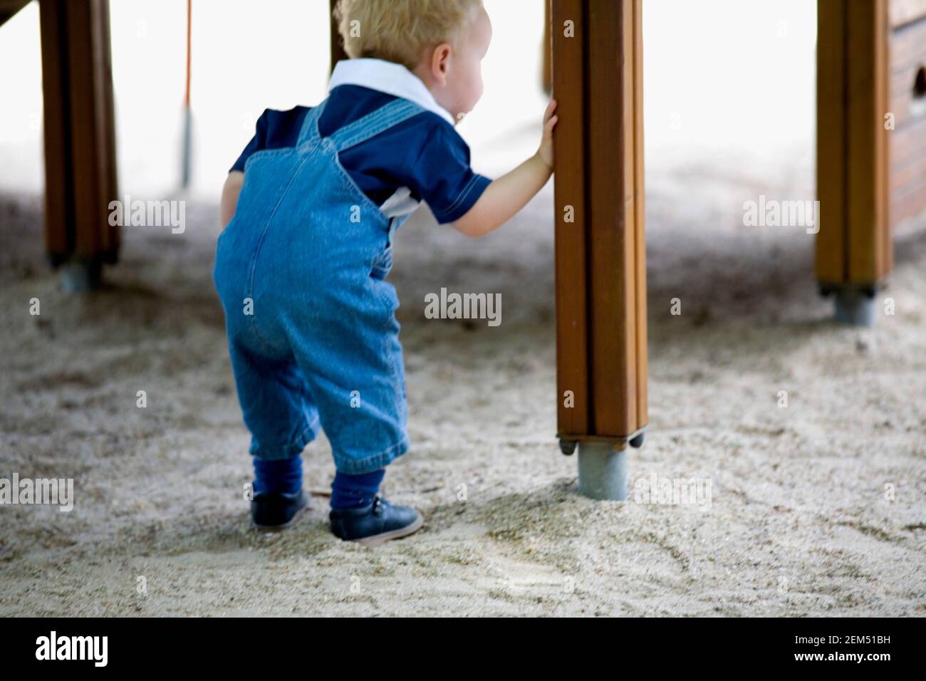 Rückansicht eines Jungen, der unter einer Holzkonstruktion guckt, Madrid, Spanien Stockfoto
