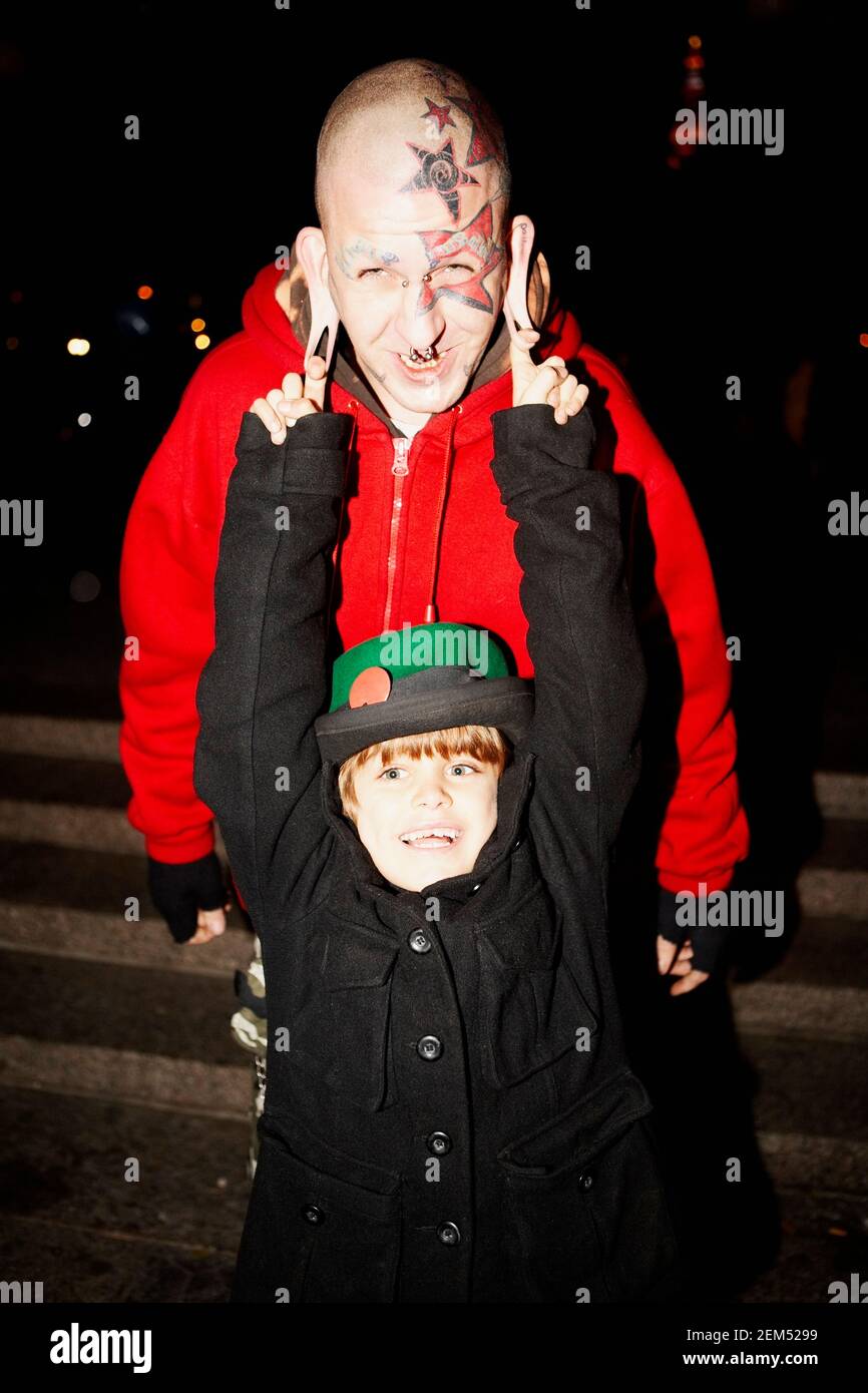 Porträt eines Jungen, der das Ohr eines mittleren erwachsenen Mannes zieht Stockfoto