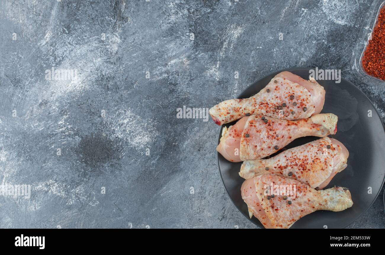 Rote scharfe Chilischote und marinierte rohe Hähnchenschenkel Stockfoto