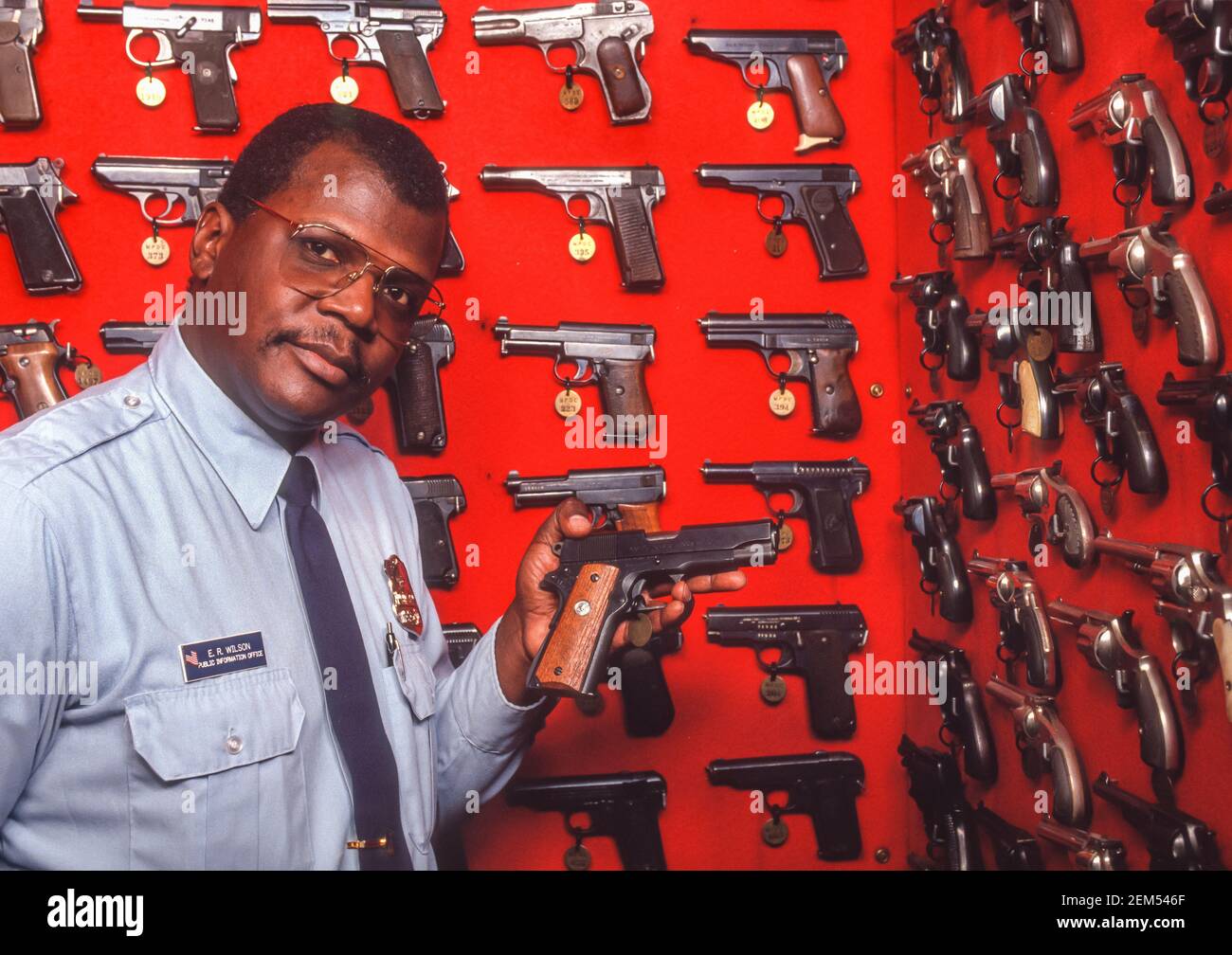 WASHINGTON, DC, USA - Polizeibeamter hält eine Handfeuerwaffe vor der Ausstellung beschlagnahmter Waffen, die von DC's Metropolitan Police Department, MPD, auf den Straßen beschlagnahmt wurden. Stockfoto