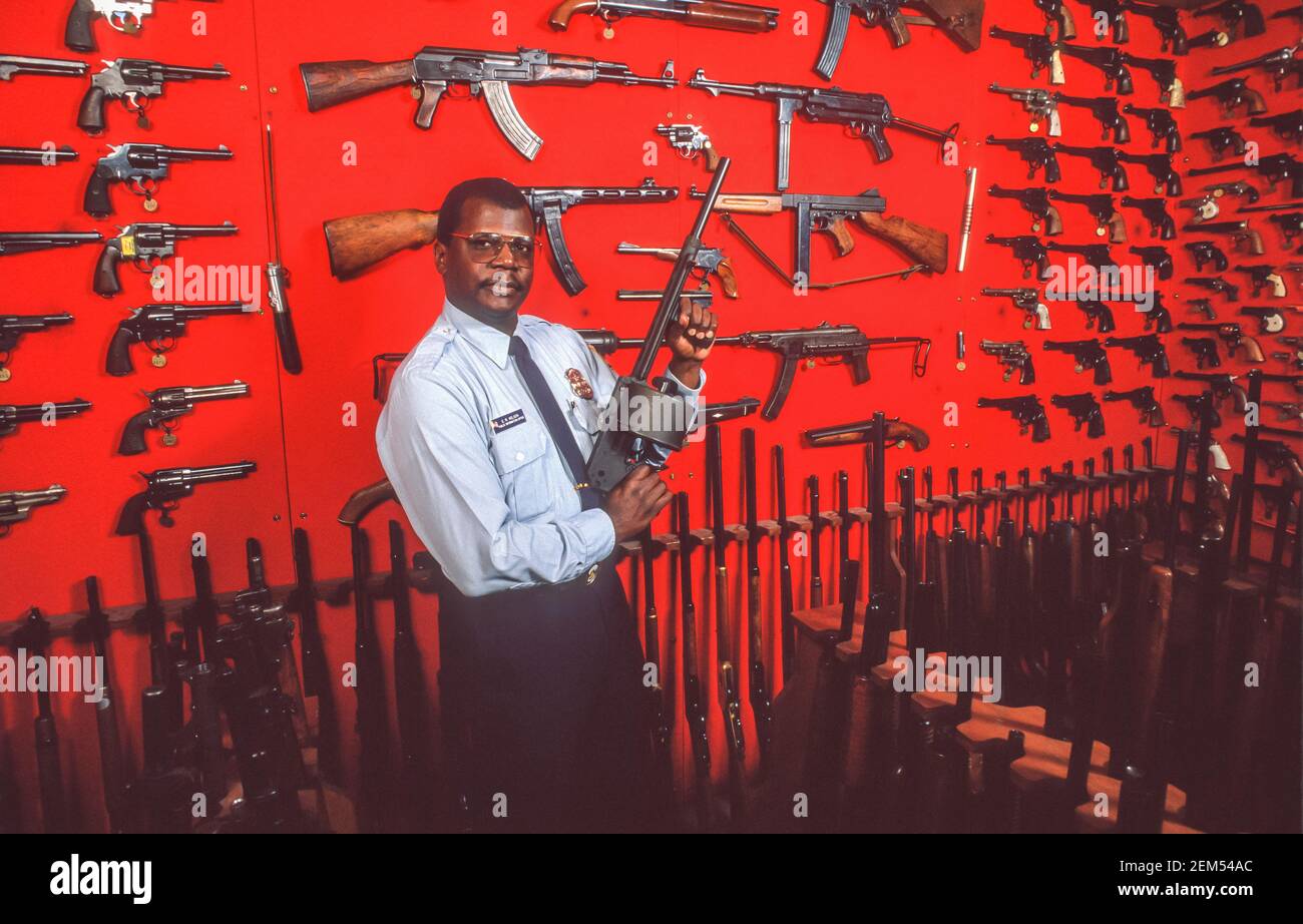 WASHINGTON, DC, USA - Polizeibeamter hält die Waffe vor der Ausstellung beschlagnahmter Waffen, die von DC's Metropolitan Police Department, MPD, auf den Straßen beschlagnahmt wurden. Stockfoto
