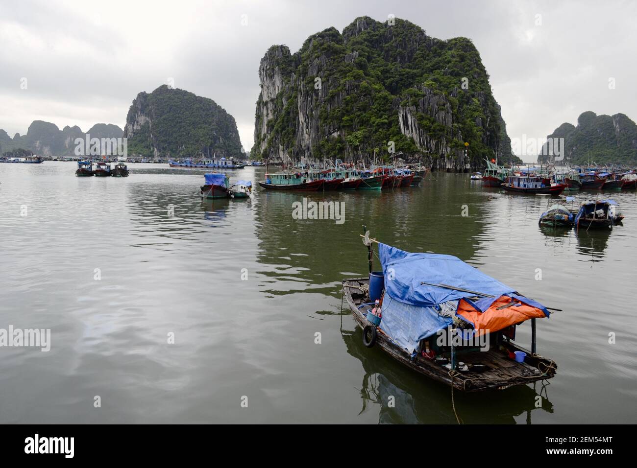 Fischerboote in Halong Bay (Ha Long Bay) - UNESCO-Weltkulturerbe und beliebtes Reiseziel. Vietnam. Schwimmendes Dorf in der Nähe von Kalksteinfelsen Stockfoto