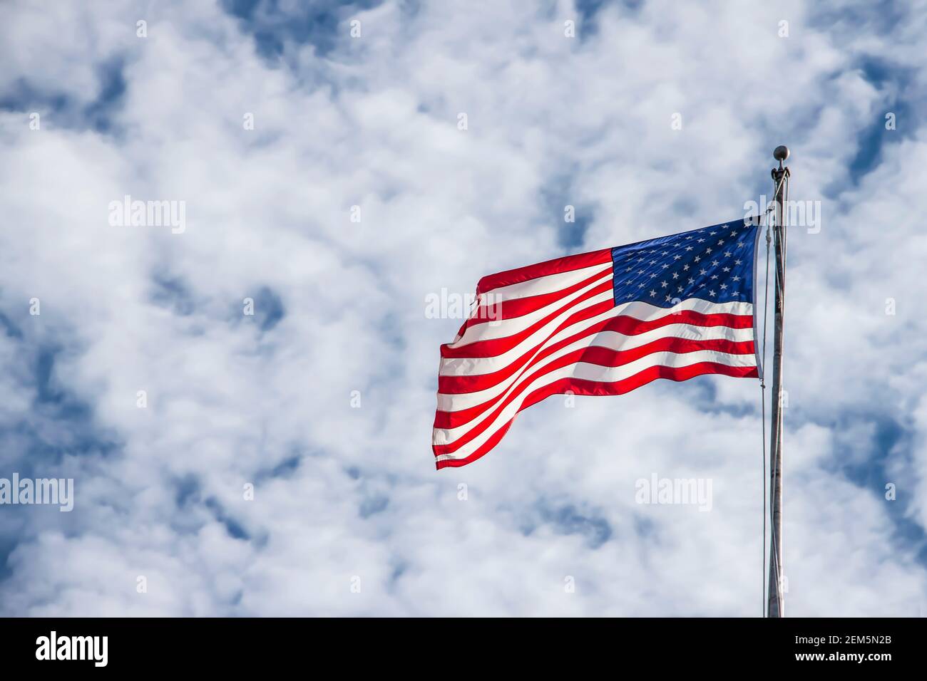 Winkende amerikanische Flagge auf Fahnenmast gegen dramatischen geschwollenen Wolkenhimmel - Raum für Kopie. Stockfoto