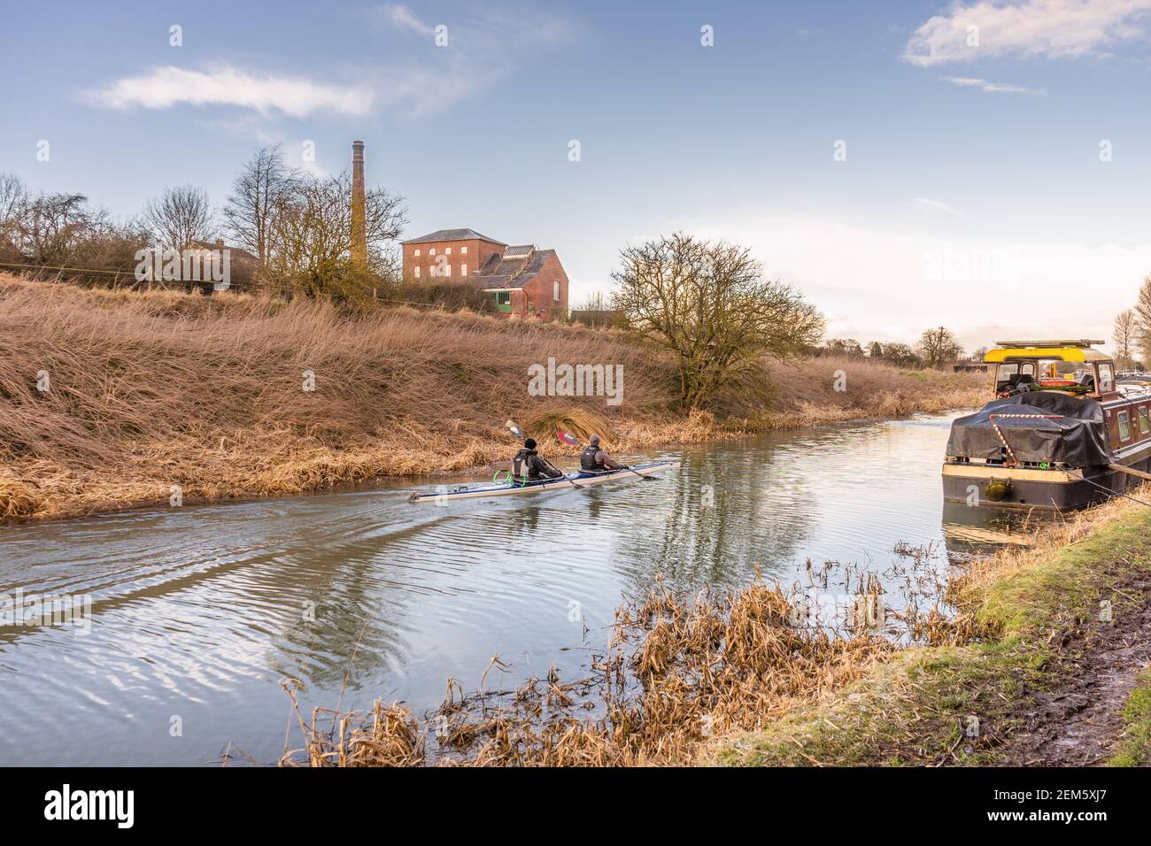Leute Kanufahren auf dem Kennet und Avon Kanal in Wiltshire mit dem Crofton beam Motoren Pumpstation im Hintergrund, Wiltshire, England, Großbritannien Stockfoto