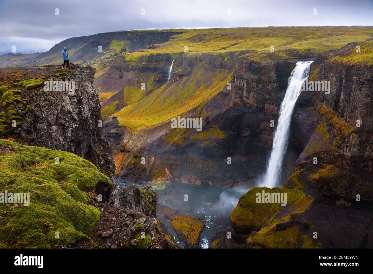 Wanderer, der am Rande des Haifoss Wasserfalls steht Island Stockfoto
