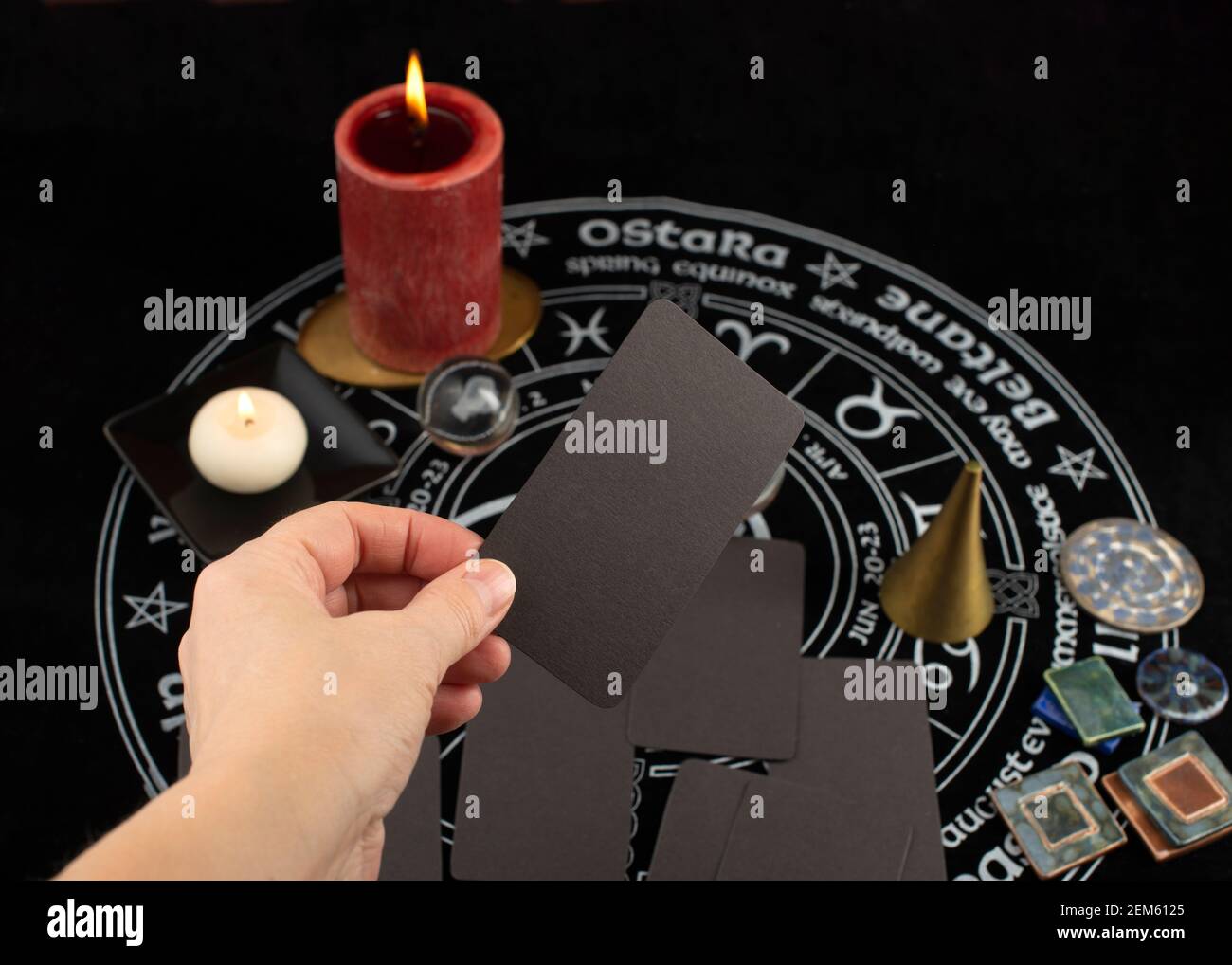 Hand hält leere Karte vor mystischem Hintergrund mit okkulten und magischen Objekten. Wahrsagerei und Wahrsageritual. Stockfoto