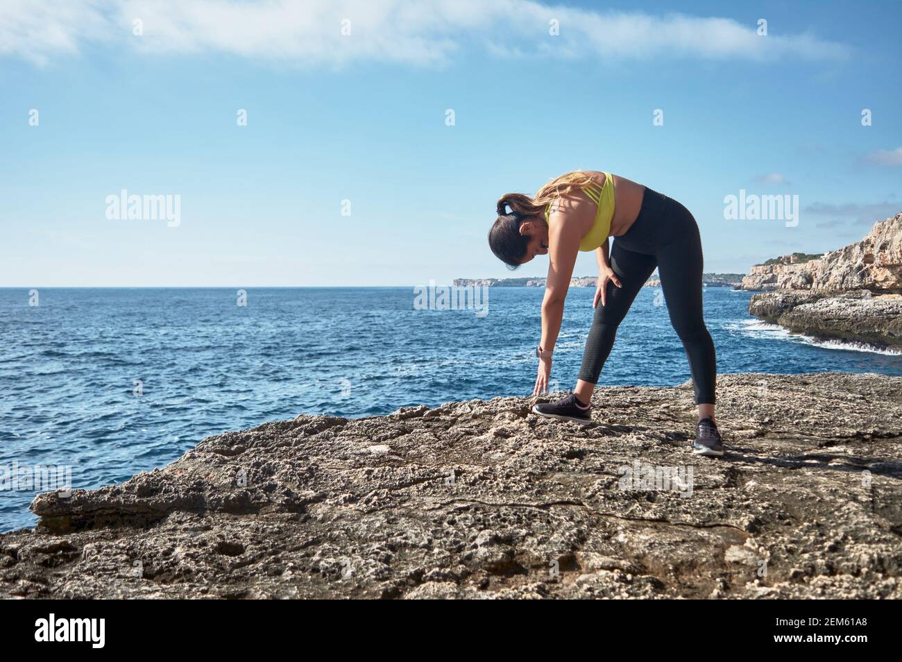 Lateinische Frau mittleren Alters, mit gelber Spitze, schwarzer Leuguin, Stretching, Gymnastik, Aufgewärmt für Training, Kalorien verbrennen, fit halten, draußen Stockfoto