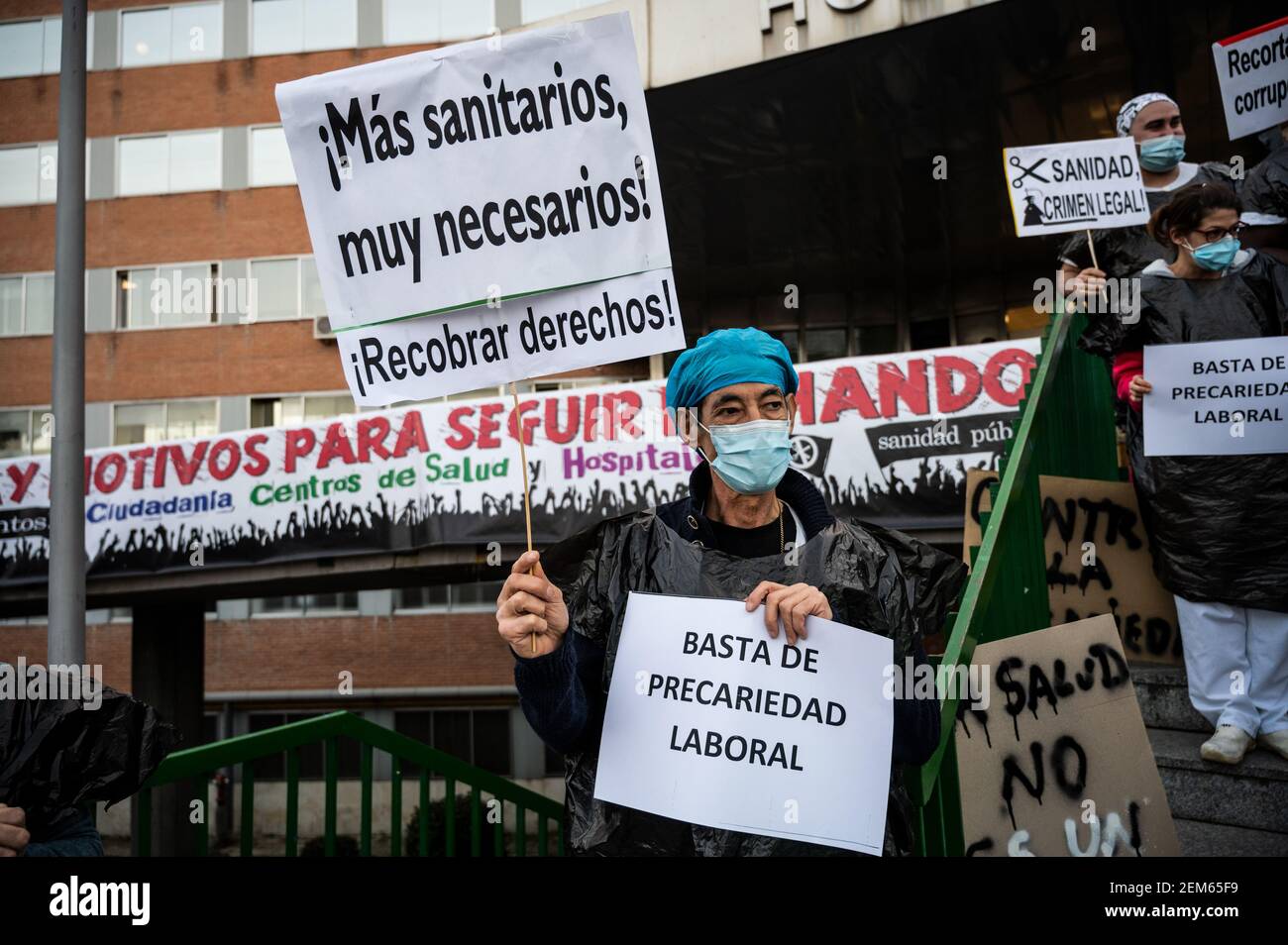 Madrid, Spanien. Februar 2021, 24th. Gesundheitshelfer protestieren mit Plakaten gegen Prekarität vor dem Krankenhaus 12 de Octubre und fordern bessere Arbeitsbedingungen und gegen ihre Misshandlung während der Coronavirus-Pandemie (CIVID-19). Gesundheitshelfer tragen Müllsäcke als Symbol des Protests. Quelle: Marcos del Mazo/Alamy Live News Stockfoto