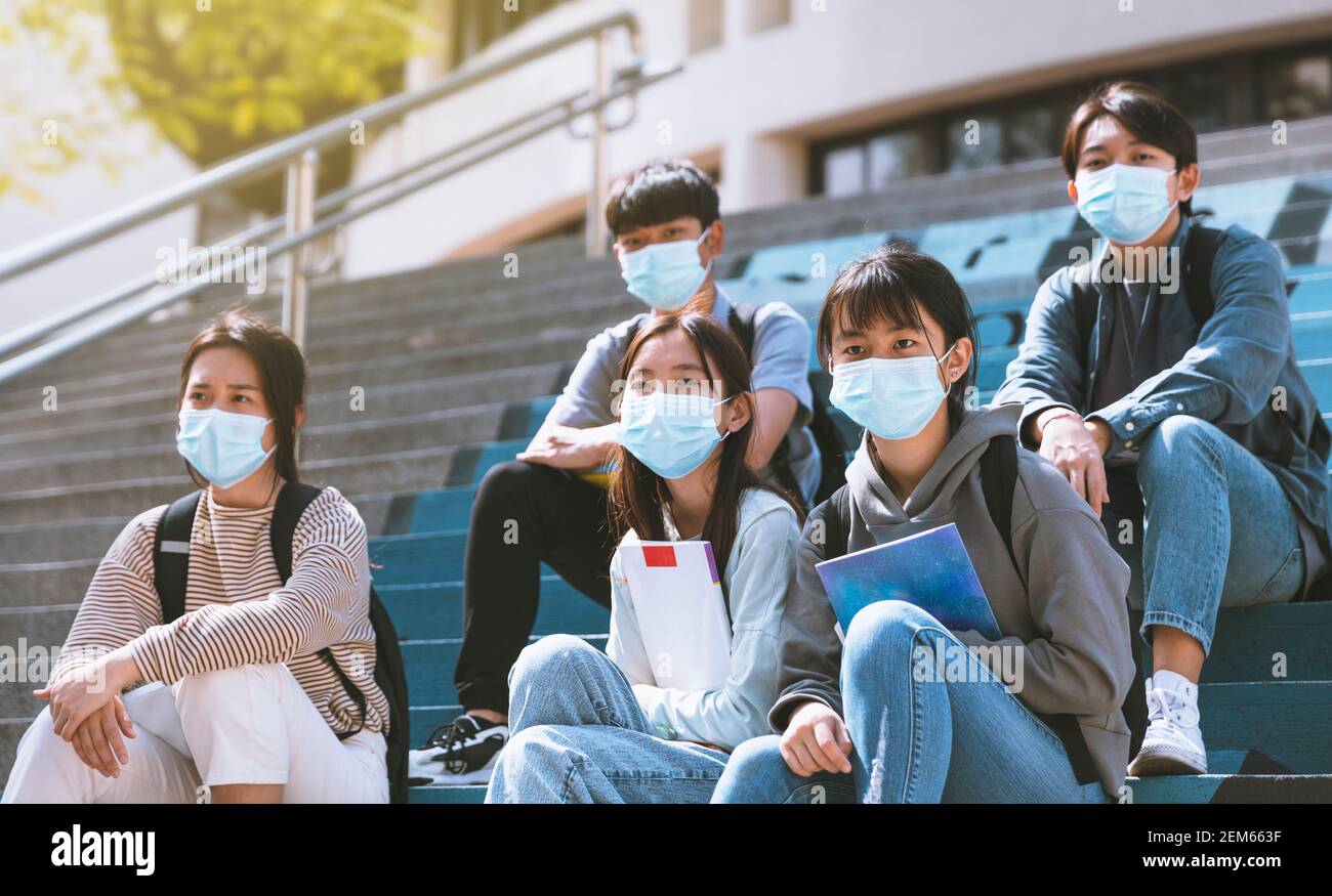 Junge Studenten tragen mit Gesichtsmasken und sitzen auf der Treppen Stockfoto