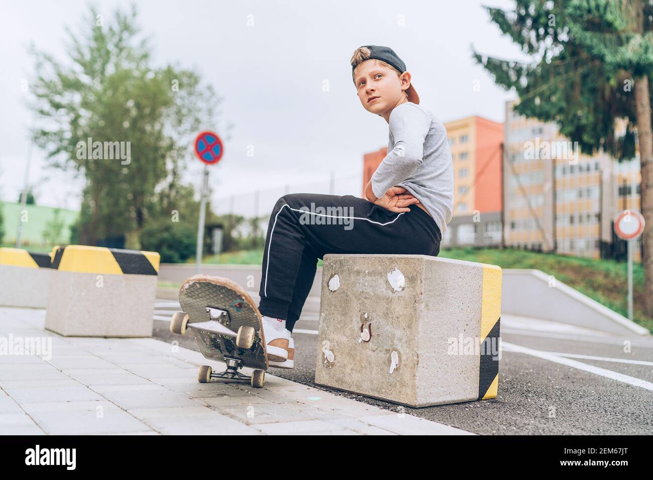 Teenager Skateboarder Junge Porträt in einer Baseball-Cap mit altem Skateboard auf der Straße der Stadt. Jugend Generation Freizeit verbringen und ein aktives Volk Stockfoto