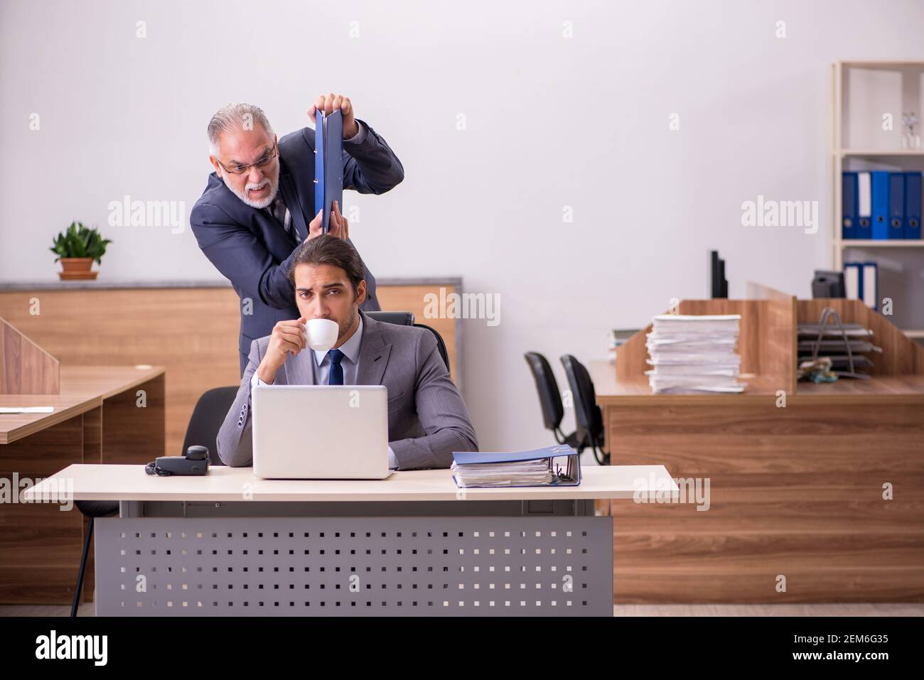 Alter männlicher Chef und junger männlicher Assistent im Büro Stockfoto