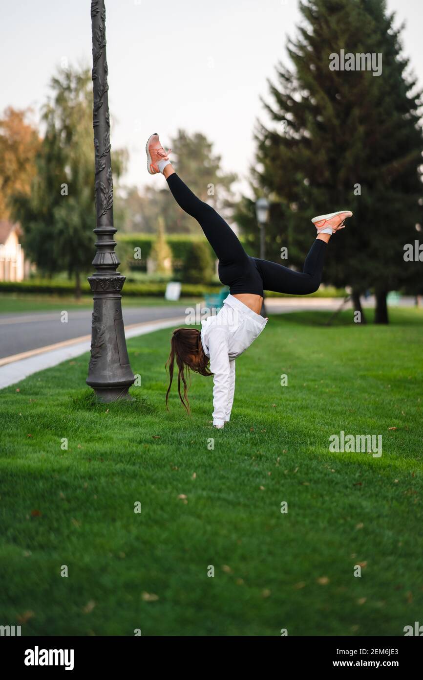 Attraktive dünne Frau tut einen Backbend, während sie einen Salto zeigt. Stockfoto