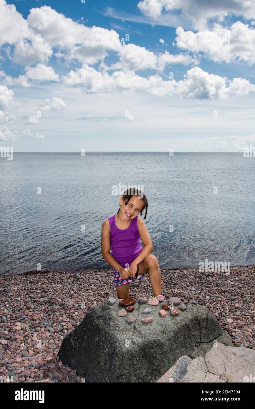 Duluth, Minnesota. 5-jährige bi-rassische Mädchen posiert vor ihrer Rock-Sammlung gesammelt, während im Urlaub am Lake Superior's Ufer. Stockfoto