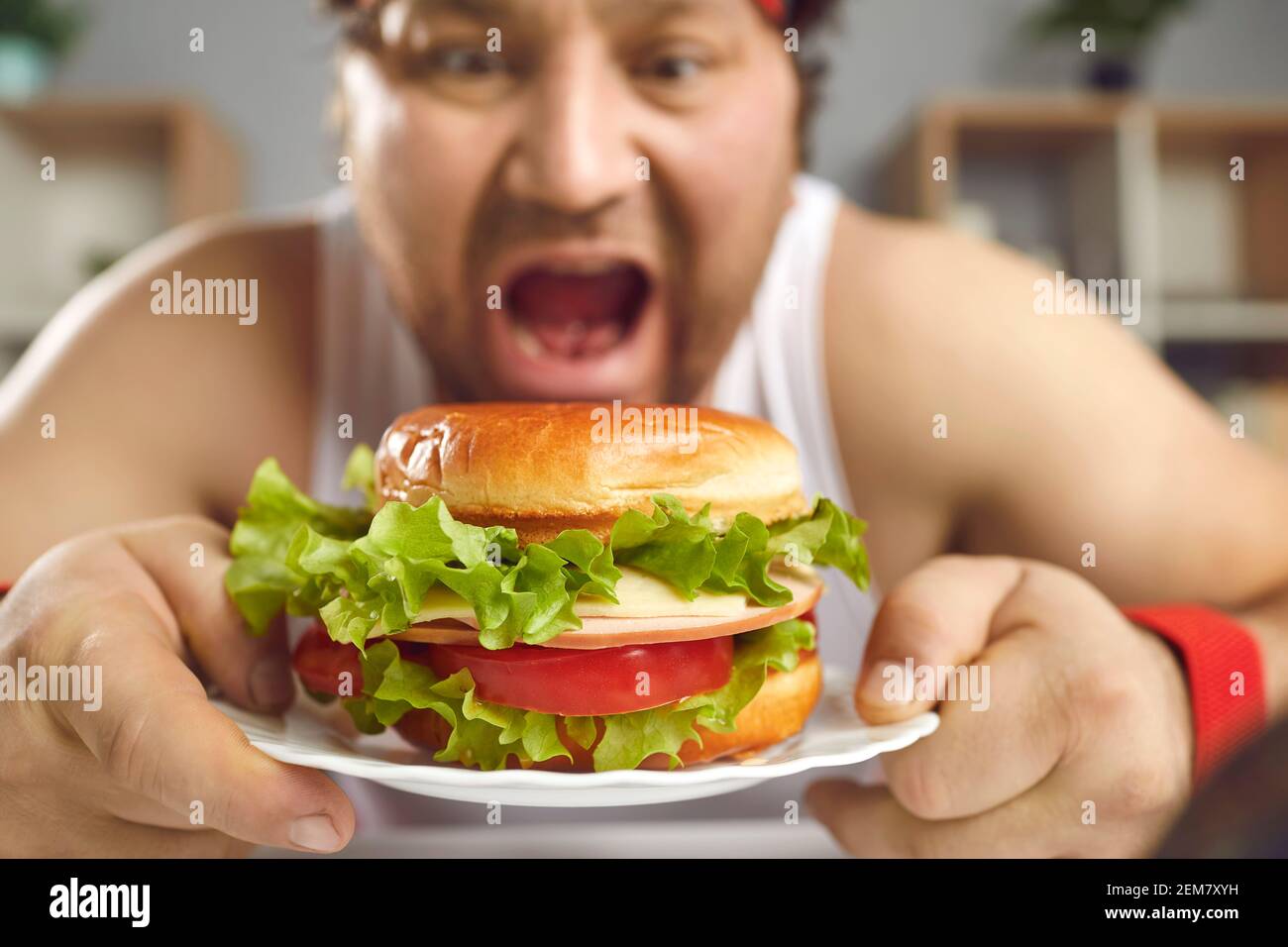 Lustige Mann, der seine Ernährung nicht genießen Fast-Food-und Essen große leckere Burger Stockfoto