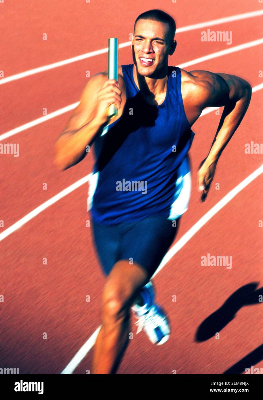 Ein Athlet sprintet mit Staffelstab in der Hand. Stockfoto