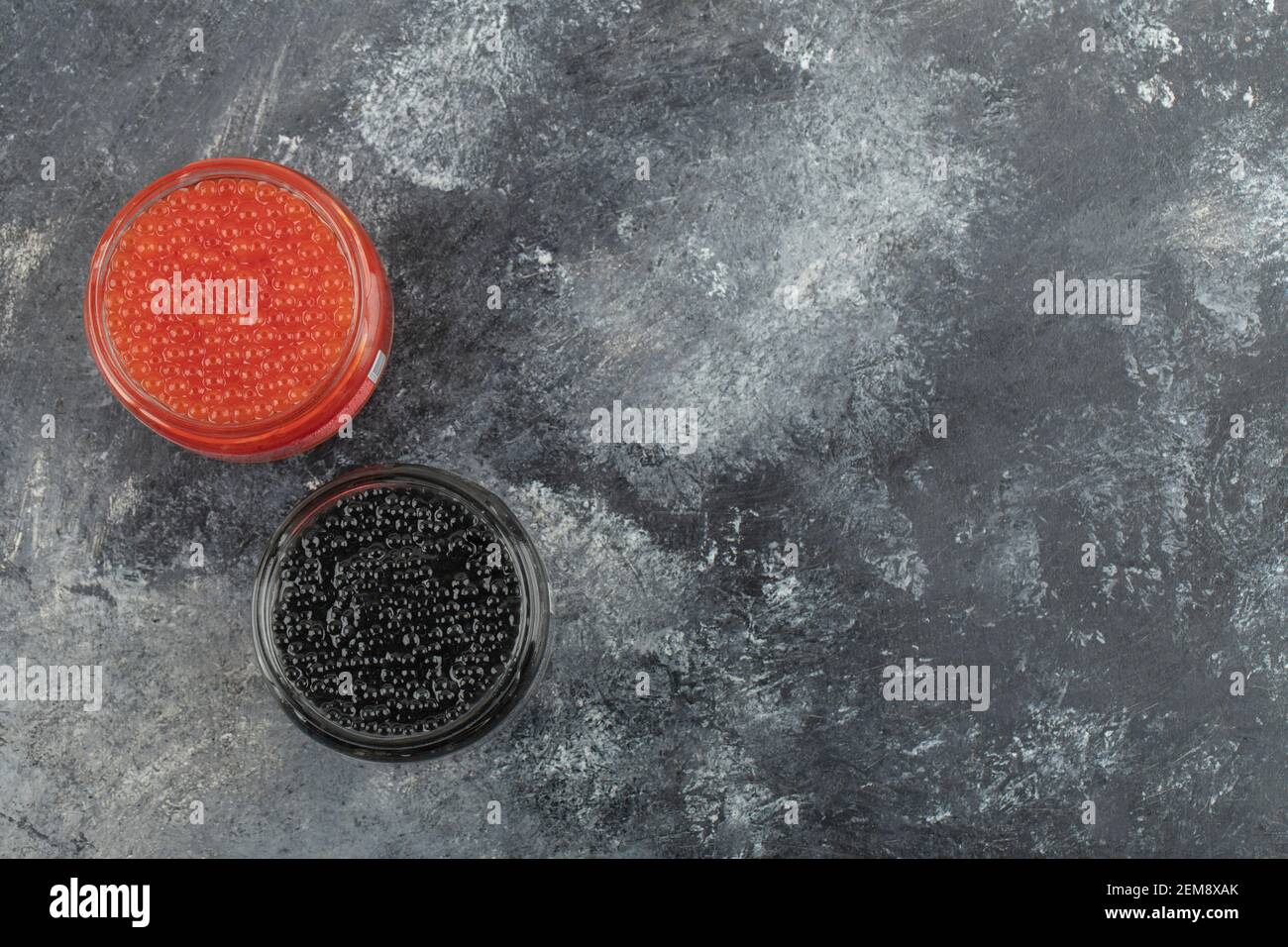 Glasplatten voll von rotem und schwarzem Kaviar auf einem Marmorhintergrund Stockfoto