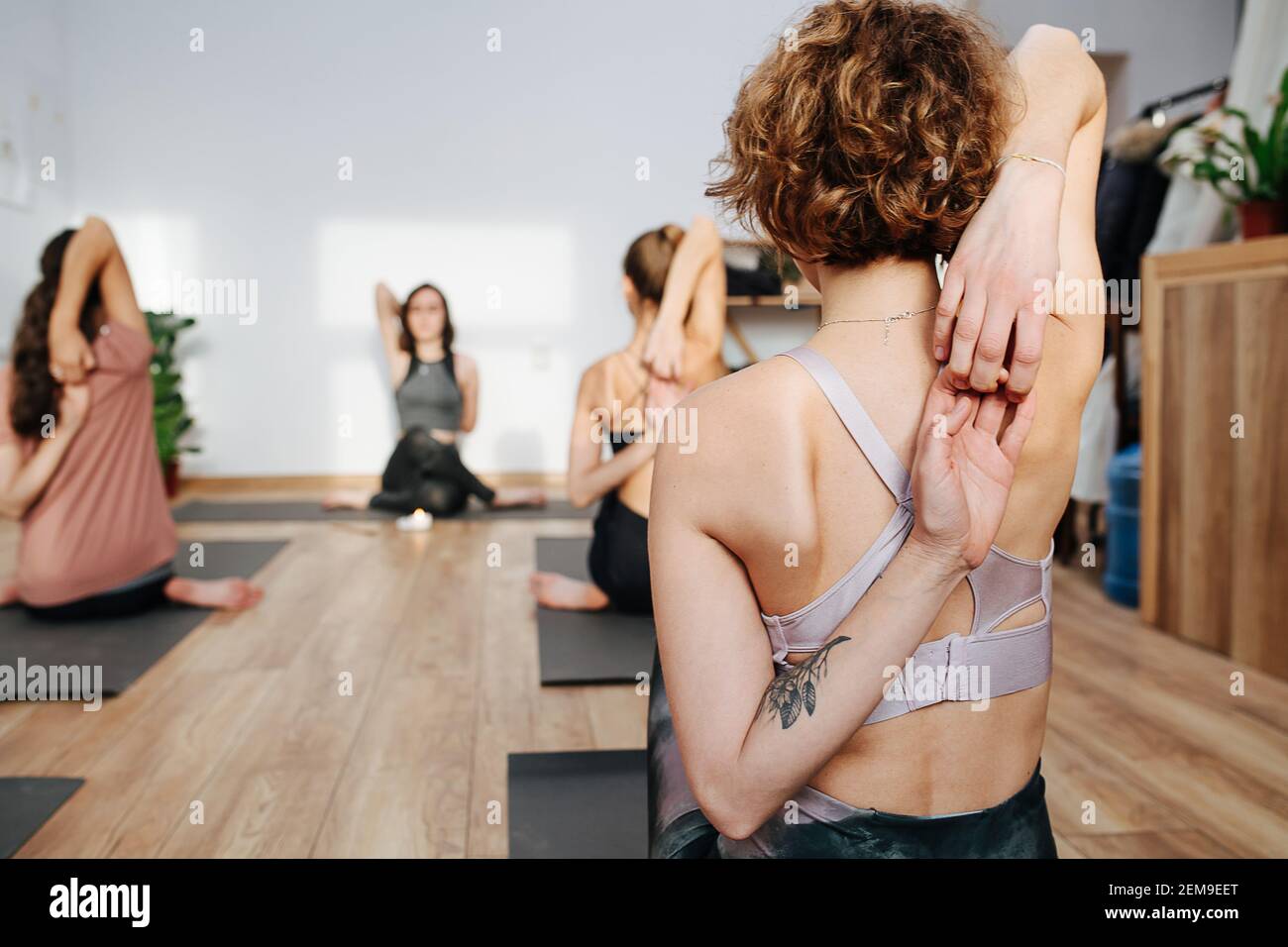 Nahaufnahme der Frau, die Yoga in einer Gruppe praktiziert und dabei die Finger verbindet Stockfoto