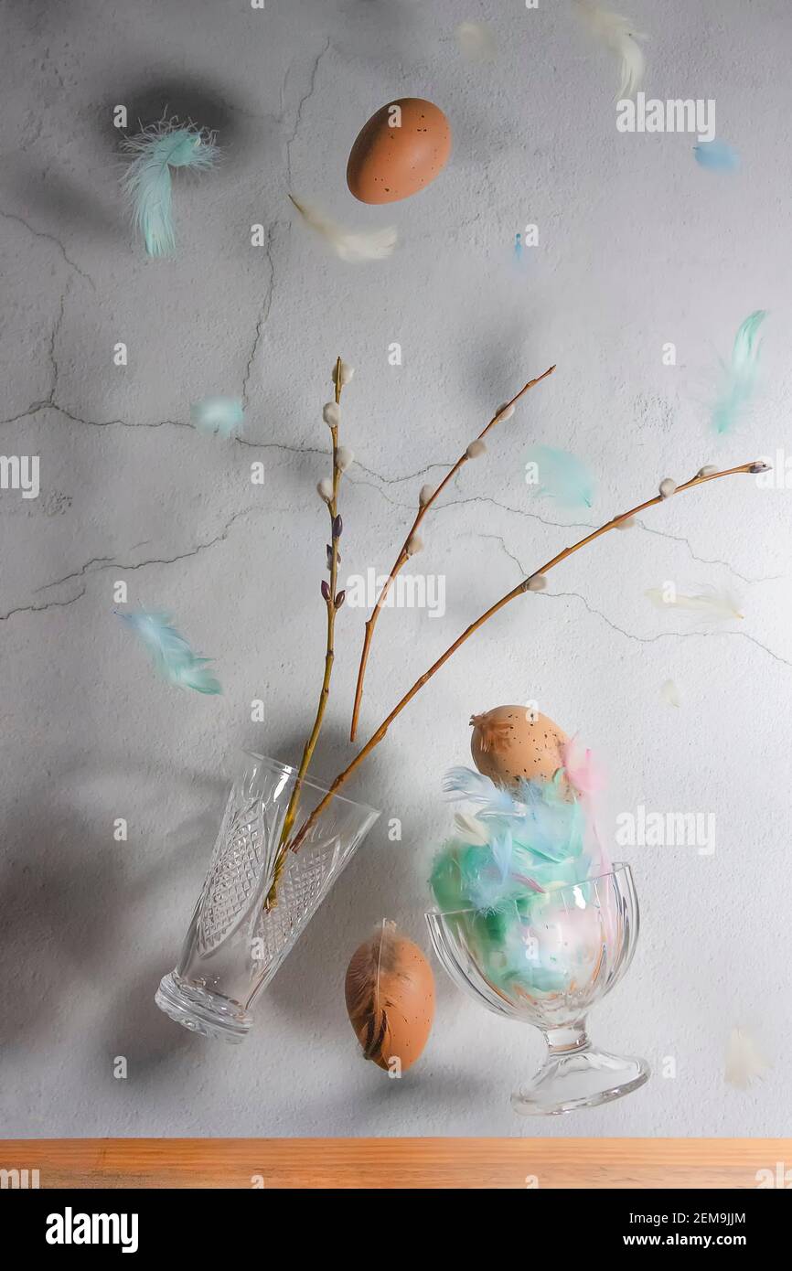 Weidenzweige, Vase, Hühnereier auf grauem Wandhintergrund. Levitationseffekt. Konzept, ostern. Hochwertige Fotos Stockfoto