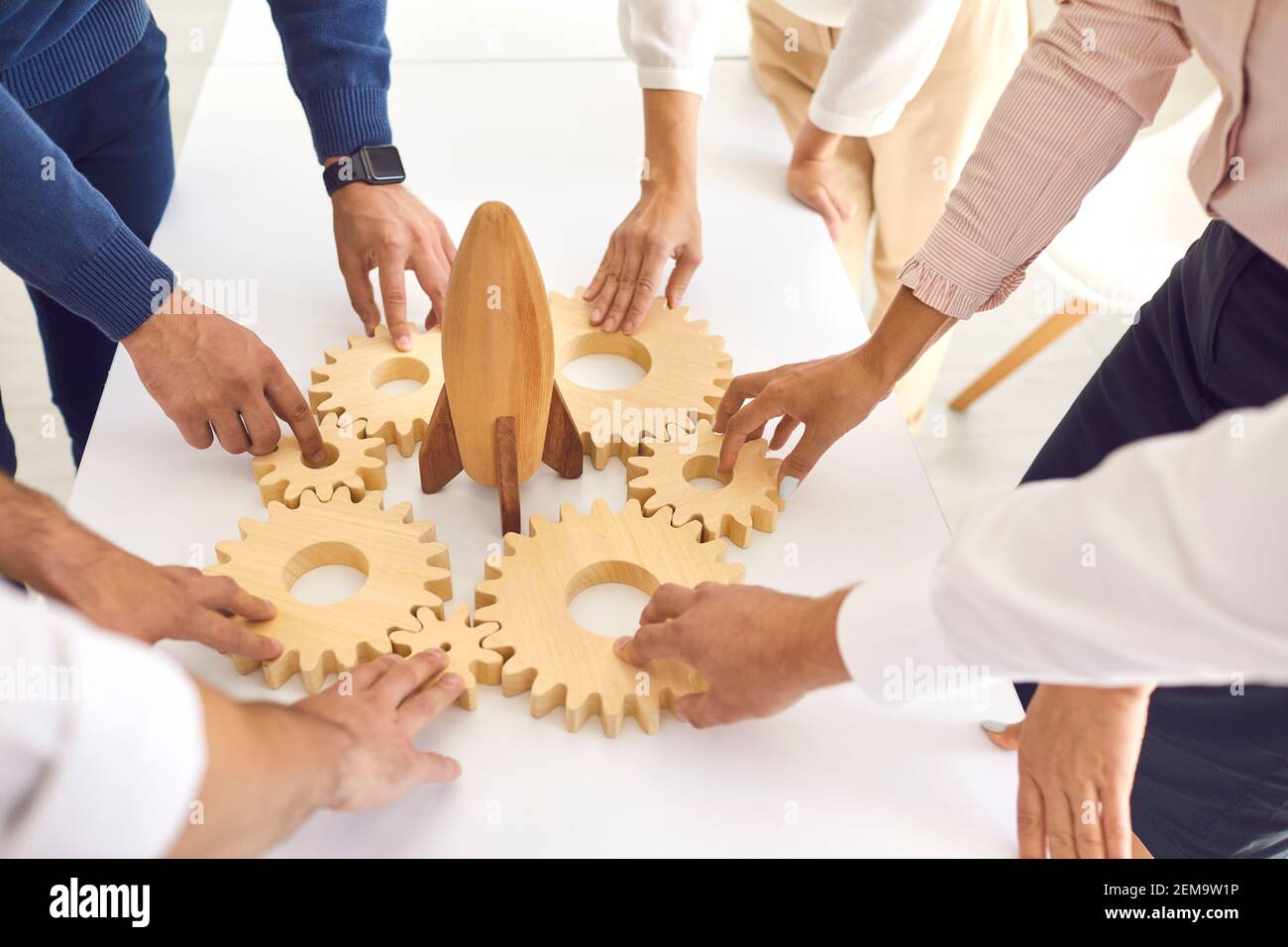 Menschen verbinden Zahnräder um Spielzeugrakete als Metapher für Teamarbeit Und ein neues Projekt starten Stockfoto