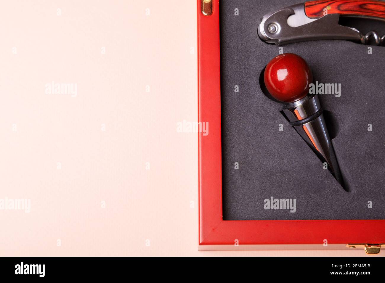 Geschenkset mit Korkenzieher und abnehmbaren Deckeln. Weinkorken und Flaschenöffner in einer Holzkiste auf rosa Hintergrund. Stockfoto