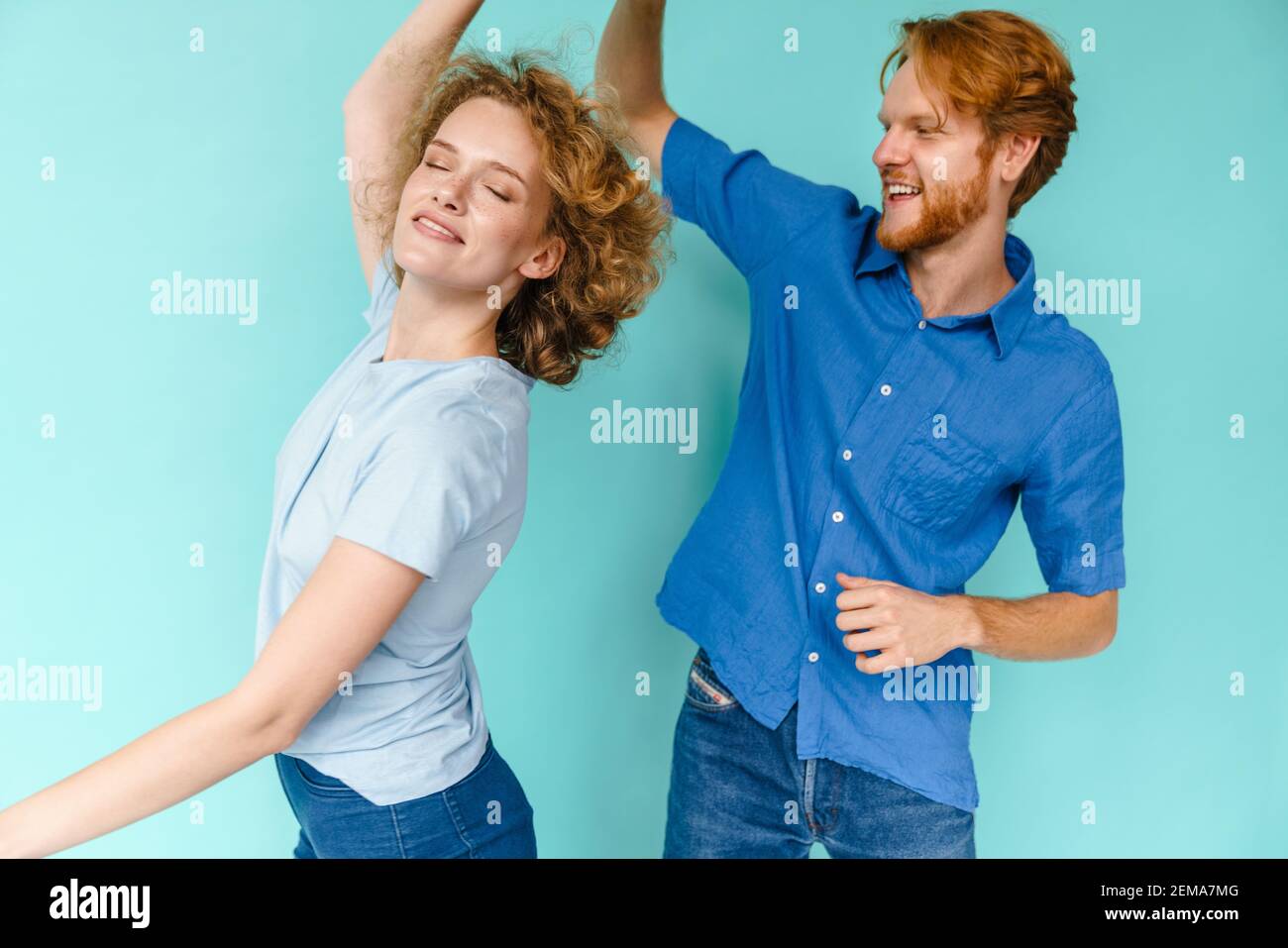 Glückliches Paar junger lustiger und glücklicher Mann und Frau tanzen im Studio auf blauem Hintergrund Stockfoto