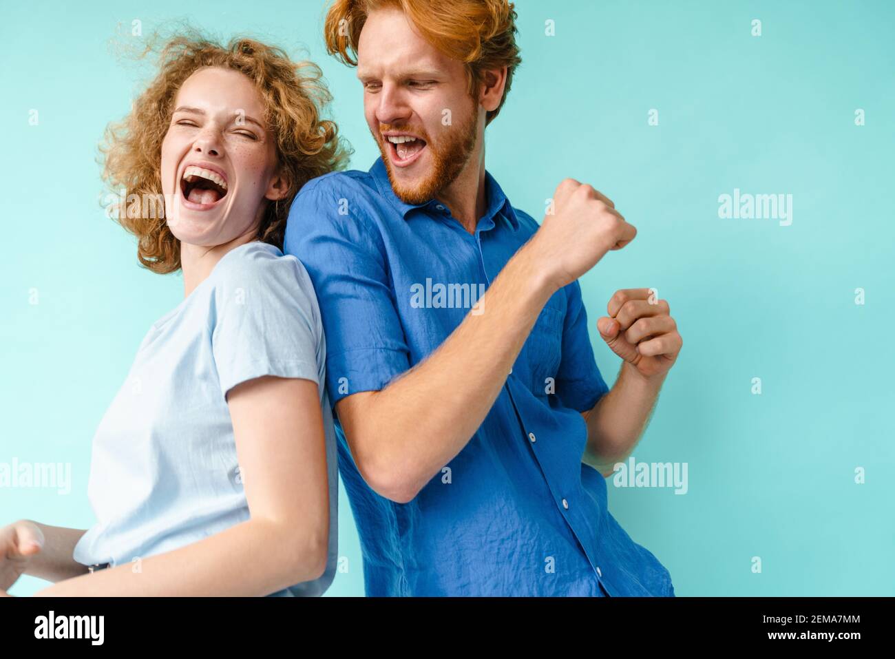 Glückliches Paar junger lustiger und glücklicher Mann und Frau tanzen im Studio auf blauem Hintergrund Stockfoto