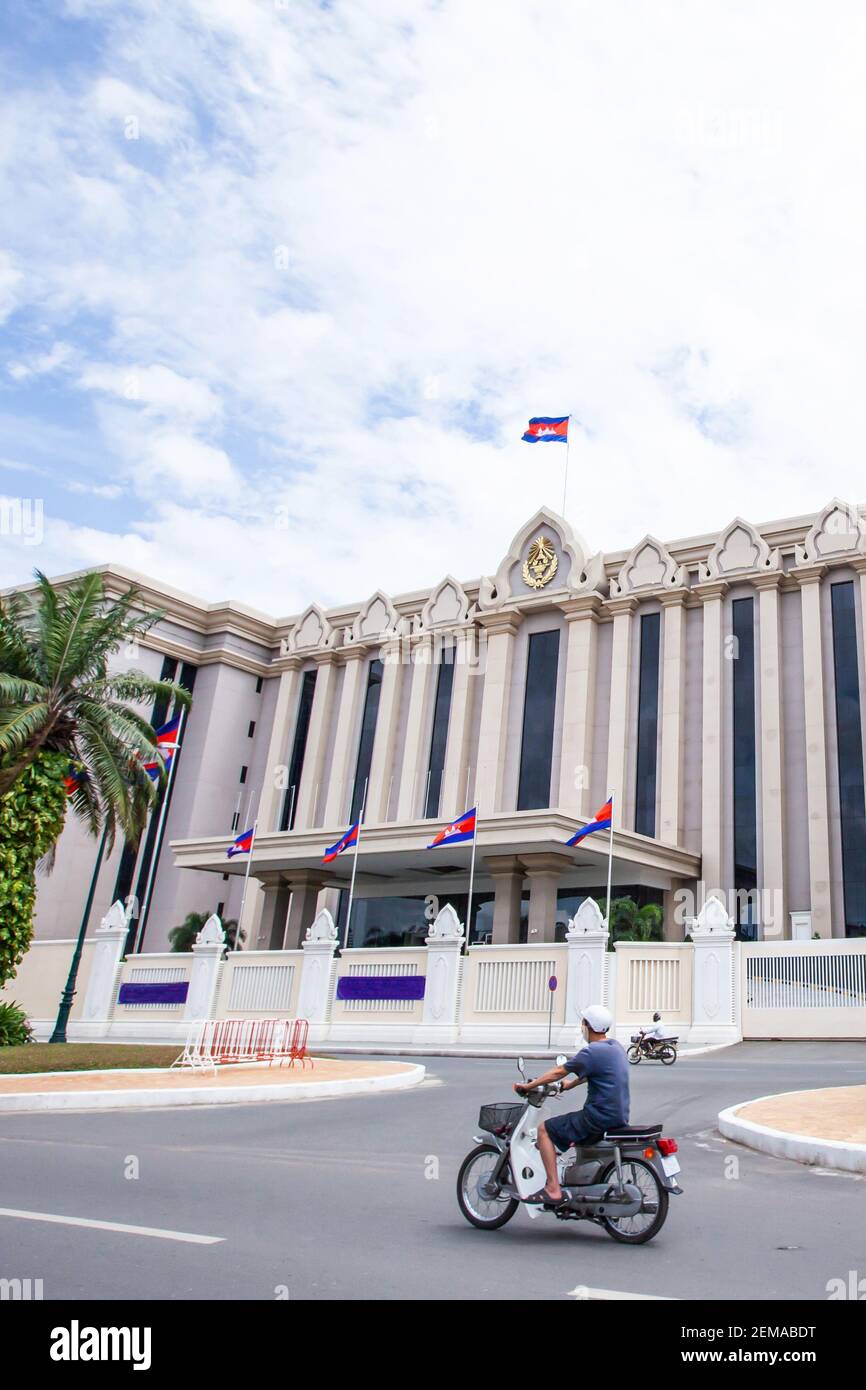 Khmer Leute fahren Motorrad passieren die Royal Government Hall von Kambodscha an sonnigen Tag. Es ist das erste moderne Regierungsgebäude nach dem Bürgerkrieg Stockfoto
