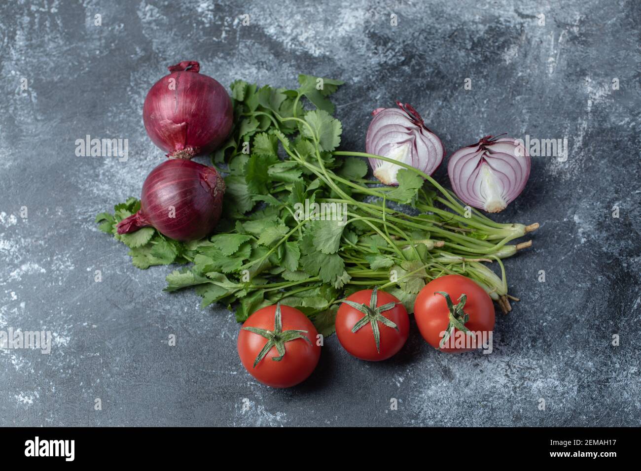 Frische rote Tomaten mit Grünpflanzen auf Marmorboden Stockfoto