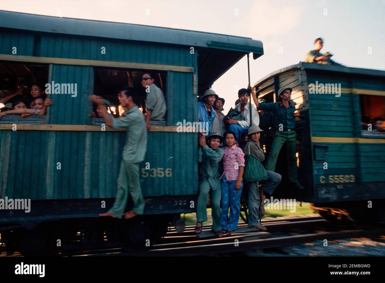 Passagiere auf einem überfüllten Dampfzug passieren einen Bahnübergang, Nordvietnam, Juni 1980 Stockfoto