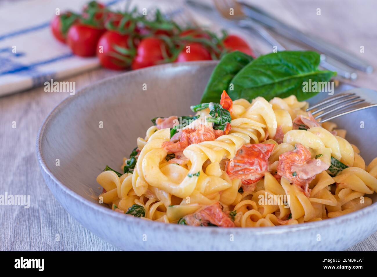 griechische Pasta mit Tomaten, Feta-Käse und Spinat auf einem Teller auf dem Küchentisch serviert Stockfoto