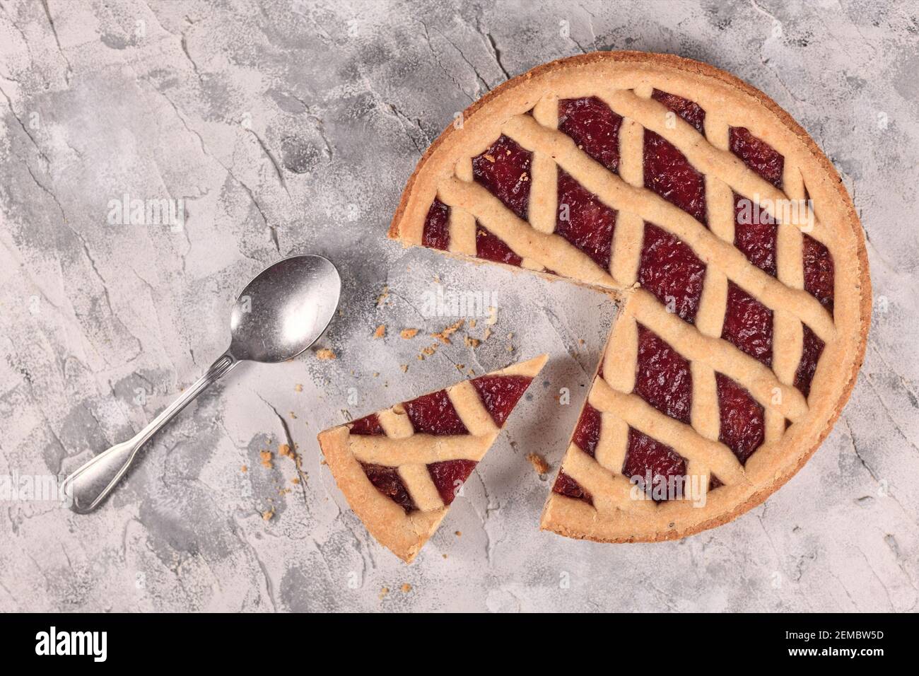 Ganze Torte namens 'Linzer Torte', ein traditionelles österreichisches Shortcake-Gebäck mit Fruchtkonserven und in Scheiben geschnittenen Nüssen mit Gitterdesign und Scheibe Stockfoto