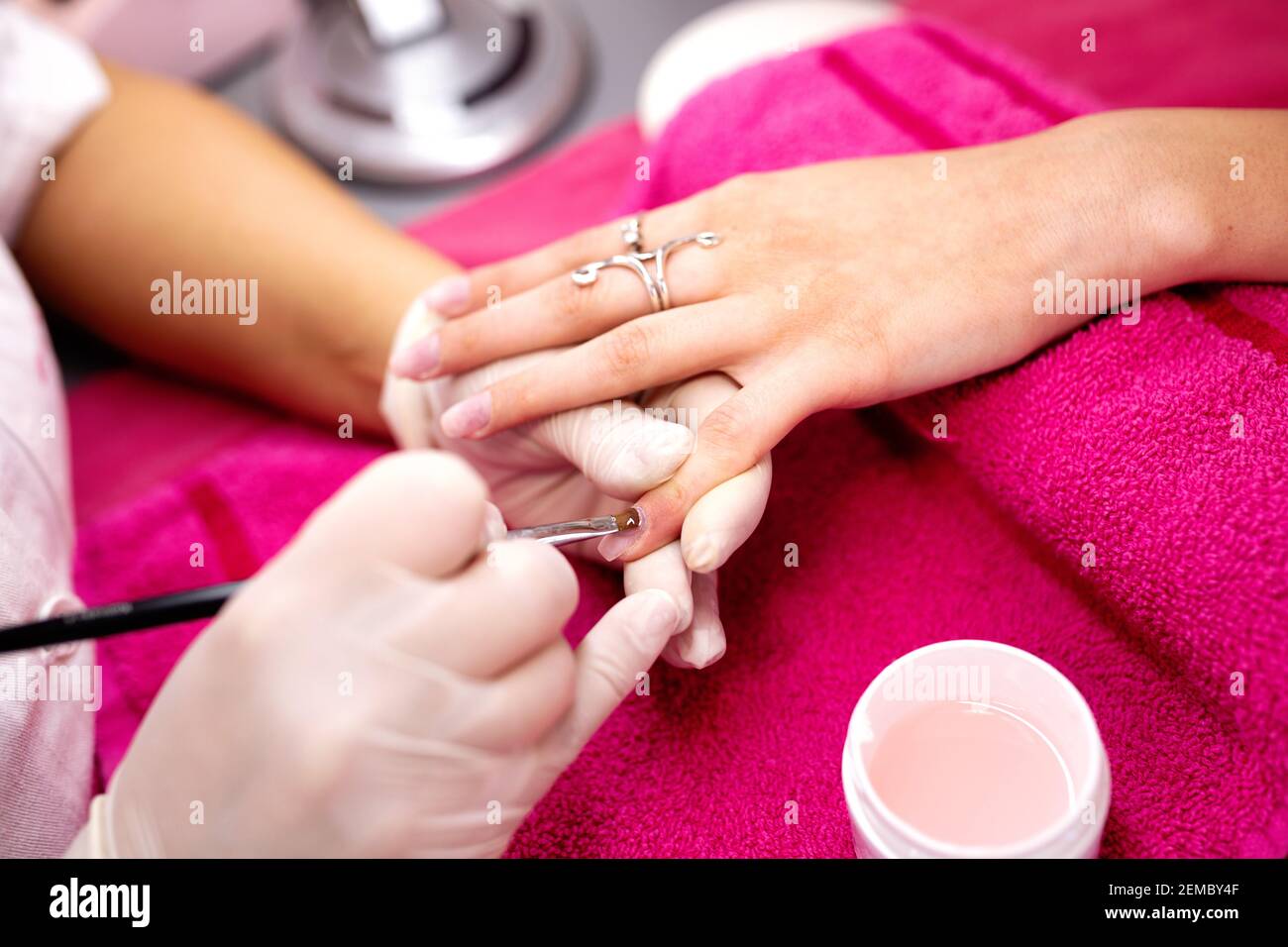 Anwendung von Gel-Basis auf der Oberfläche der Nagelplatte, Maniküre für Frauen, Nagelstudio Stockfoto