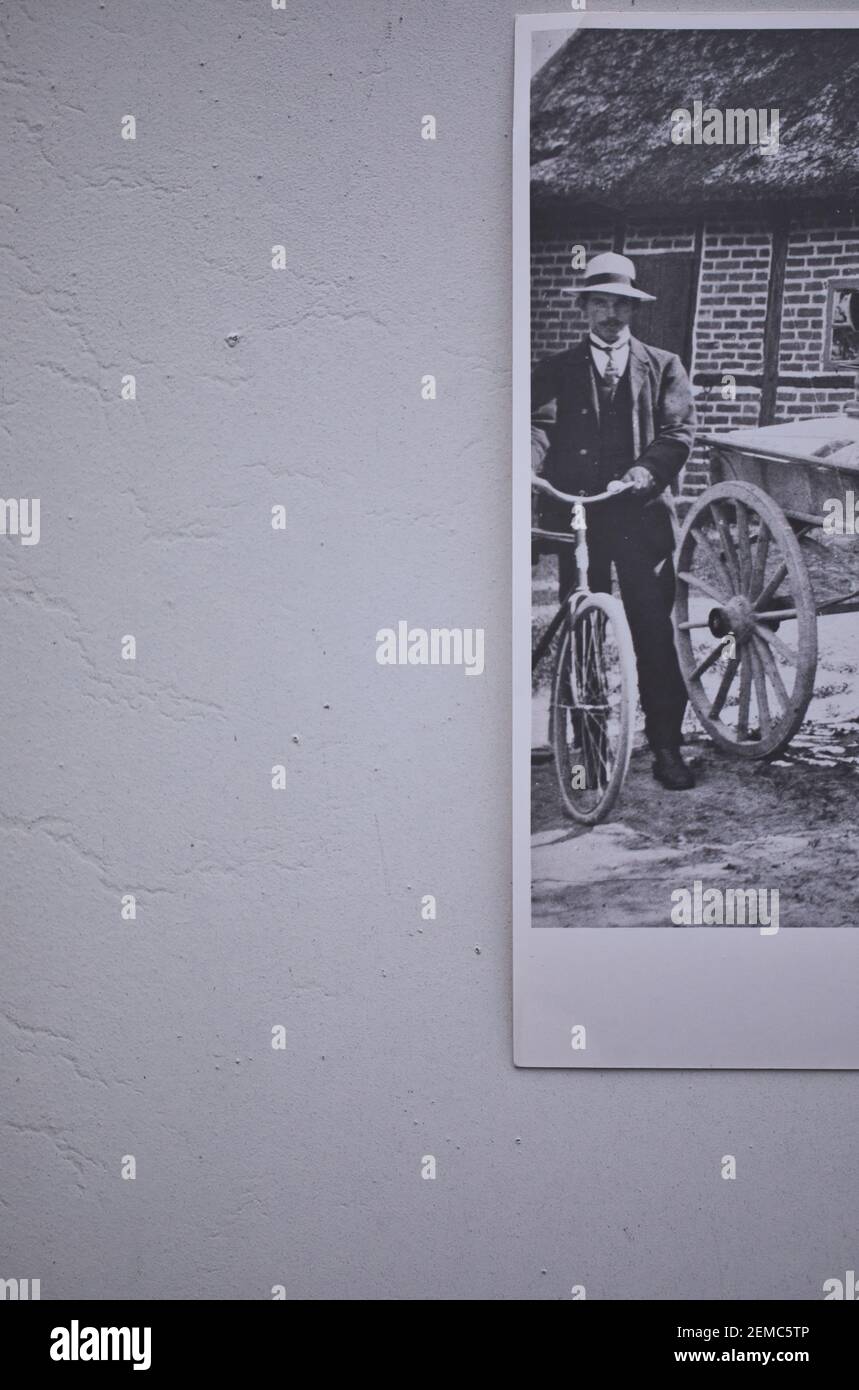 Direkt oberhalb von 1910 ländliches Schwarz-Weiß-Foto des Mannes im Hut mit Fahrrad neben dem Wagen. Konzept, ländliche Leben, 1900 Lebensstil, Transport Stockfoto