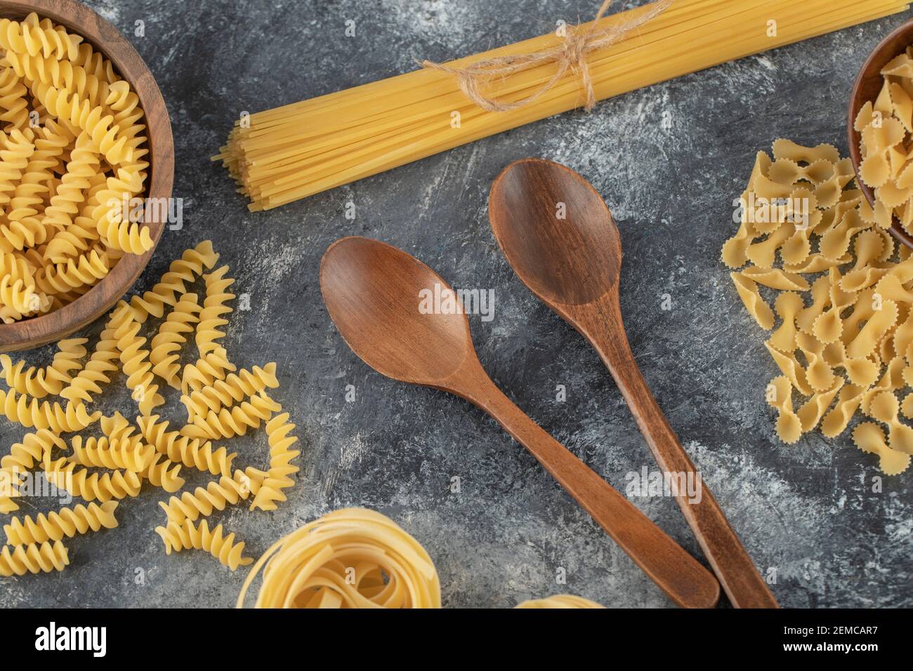 Verschiedene Arten von ungekochten Nudeln mit Holzlöffeln Stockfoto