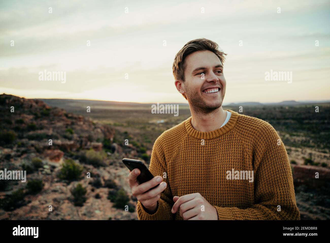 Lächelnder kaukasischer Wanderer, der in den Bergen unterwegs ist und die Natur umarmt und Bilder nimmt Mit Mobilfunkgerät Stockfoto