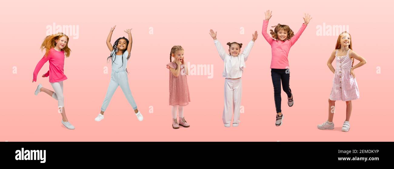 Freundschaft. Gruppe von Grundschulkindern oder Schülern springen in bunten Freizeitkleidung auf rosa Studio Hintergrund. Kreative Collage. Zurück zur Schule, Bildung, Kinderkonzept. Fröhliche Mädchen. Stockfoto