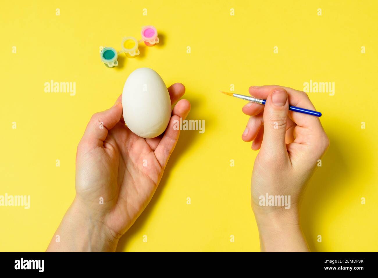 Ostereier Malerei setzen Hände. Pinsel und malen auf gelbem Hintergrund Stockfoto