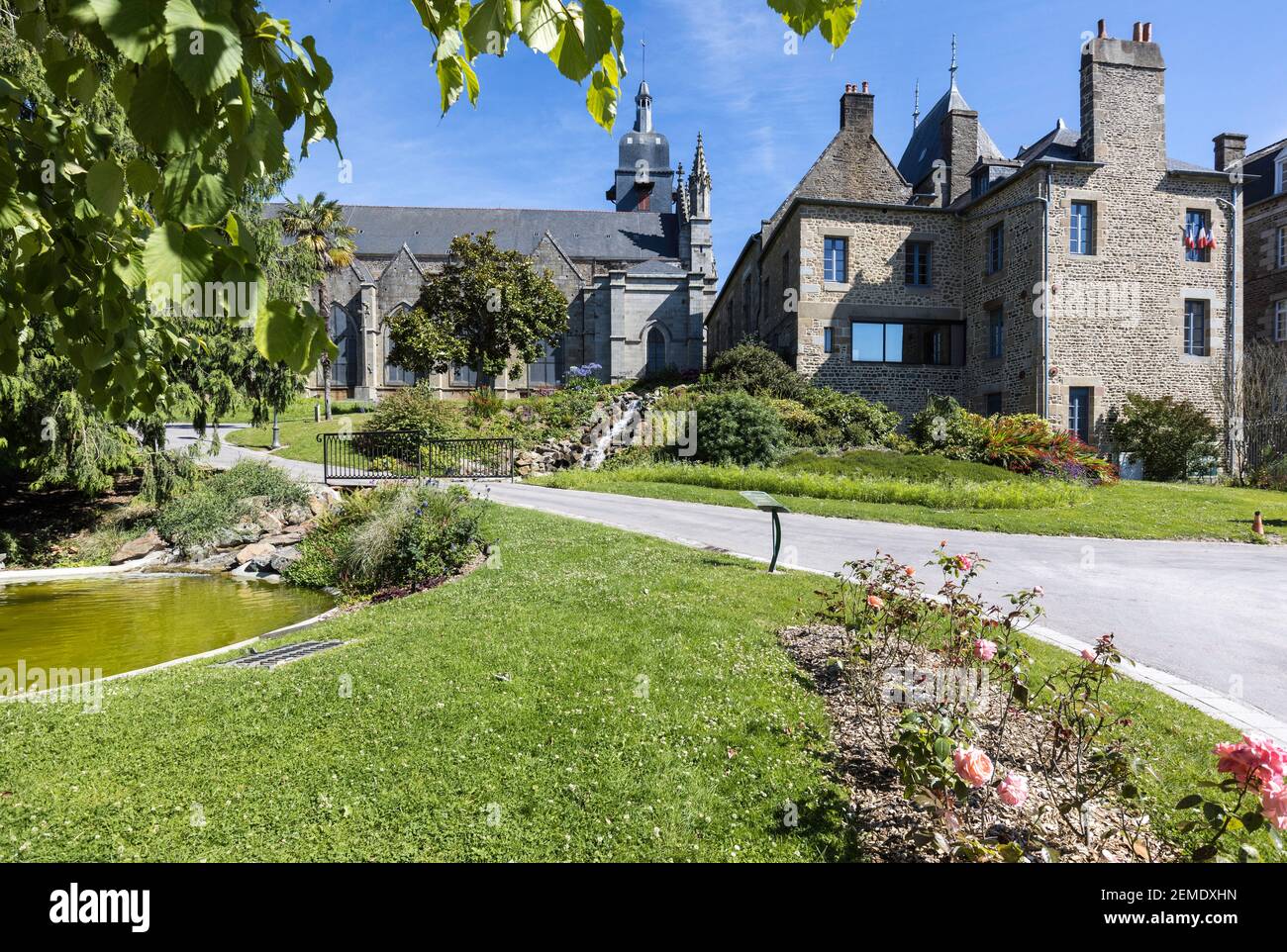 Jardin Public, Garten, in Fougeres, Frankreich bei strahlender Sommersonne, klarem blauen Himmel mit einer Kirche und anderen Gebäuden im Hintergrund, keine Menschen Stockfoto