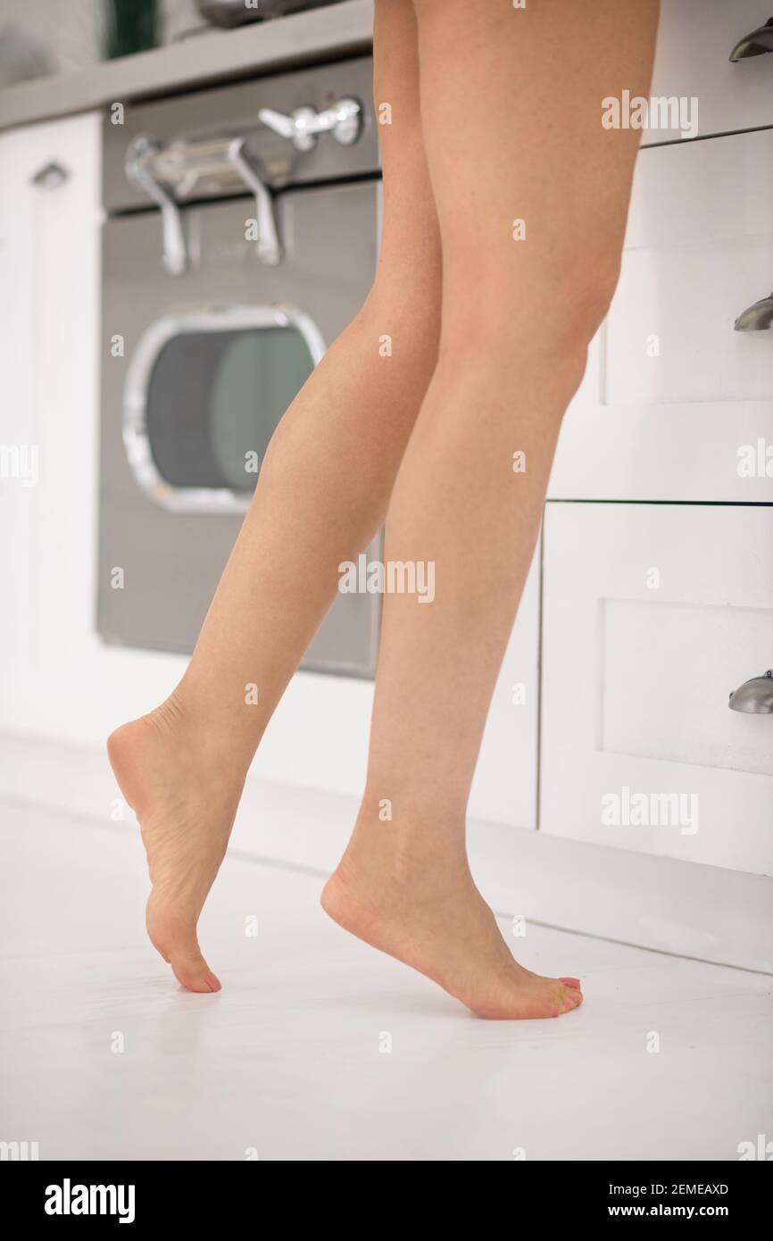 Weibliche schlanke Beine auf Zehenspitzen in der Küche Stockfoto