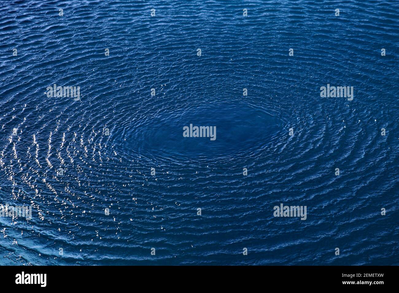 Splash: Konzentrische Kreiswellen auf blauem Süßwasser; Farbfoto. Stockfoto