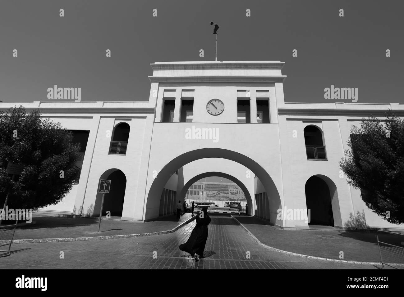 Schwarzweiß, Bild einer bahrainischen Frau in einem Abaya, die zum Tor nach Bahrain, Bab al Bahrain, Manama, Königreich Bahrain geht Stockfoto
